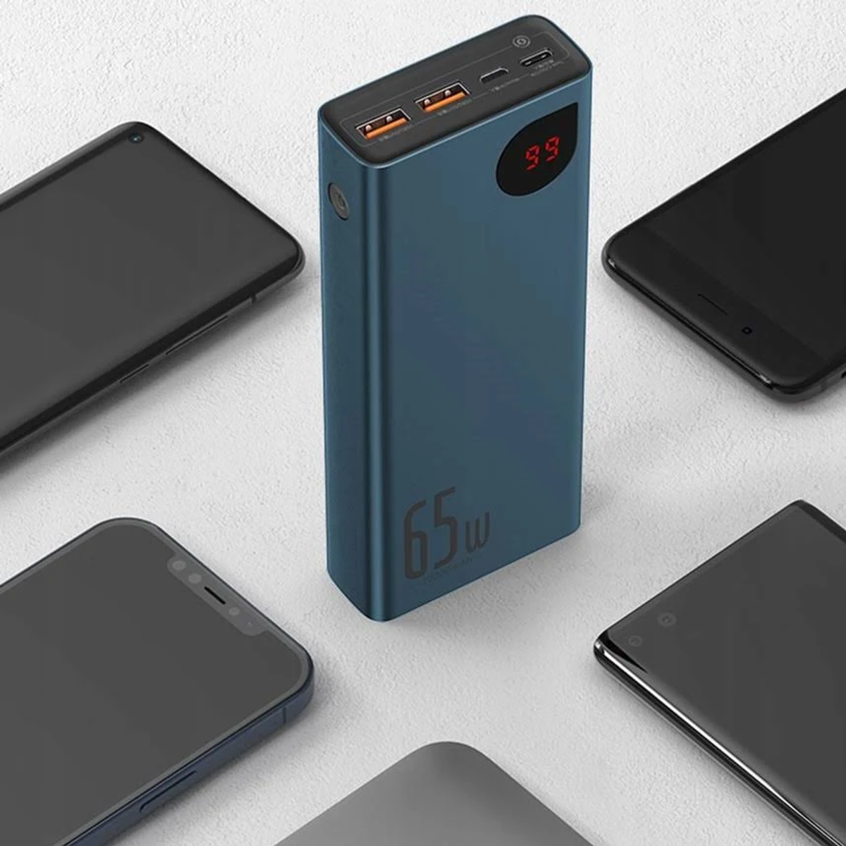 Un power bank blu con display digitale e telefoni intorno. Ha due porte USB.