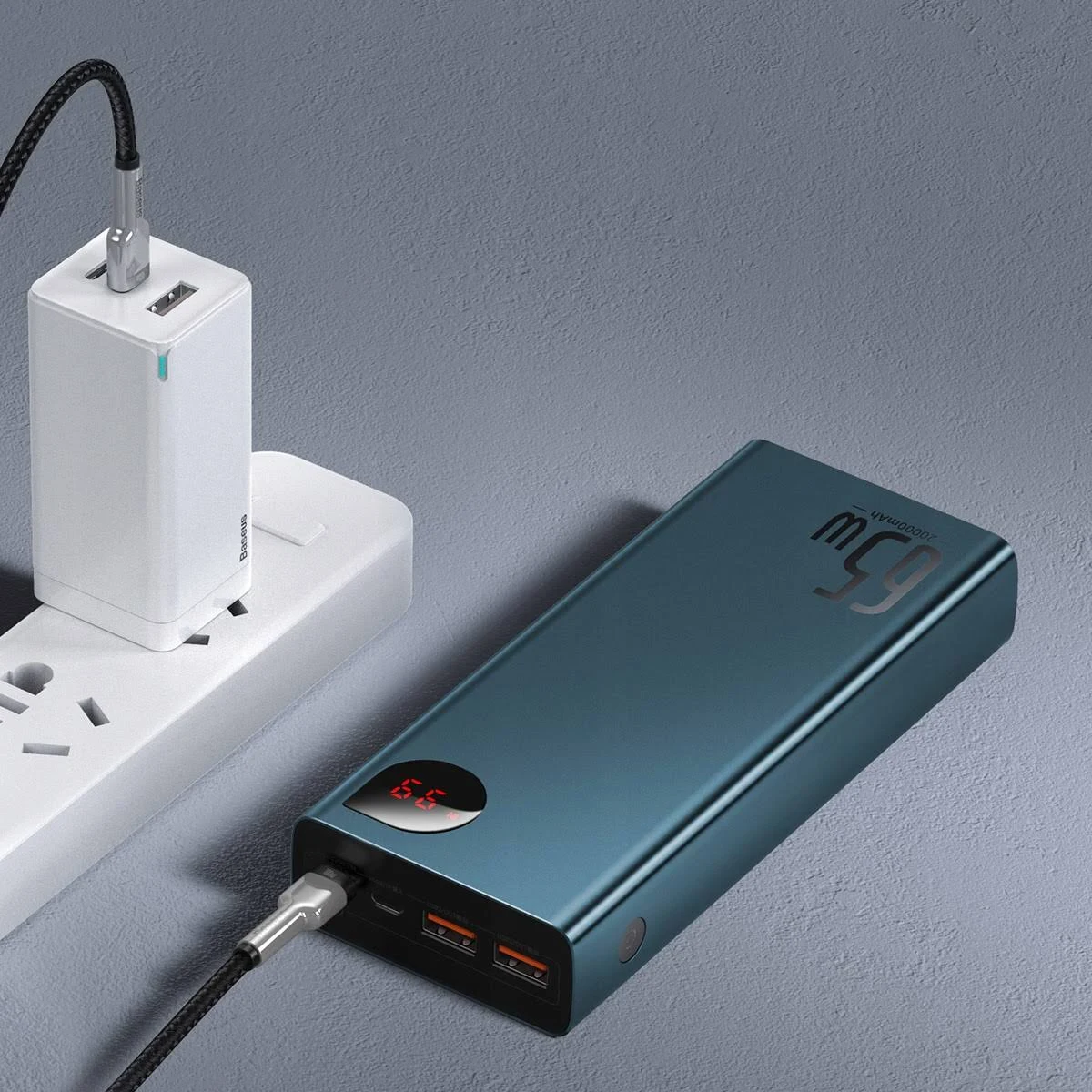 Un power bank verde acqua con un cavo di ricarica collegato a un adattatore di alimentazione bianco.