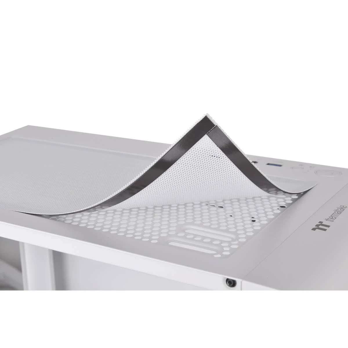 Biała obudowa komputera z odchylanym górnym panelem z siatki. Białe tło.