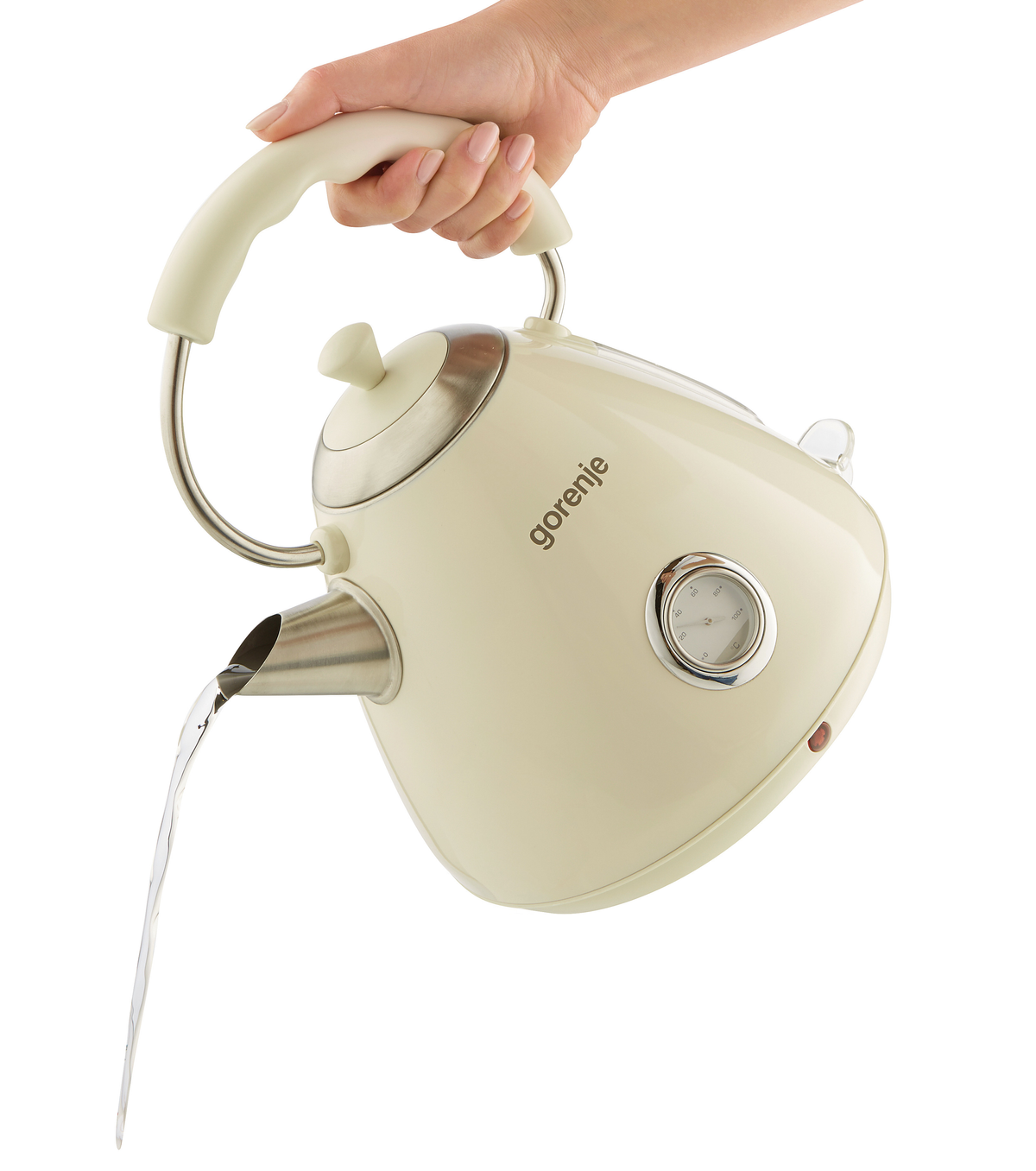 Kremowy czajnik wylewający wodę. Białe tło. Dłoń trzymająca uchwyt.