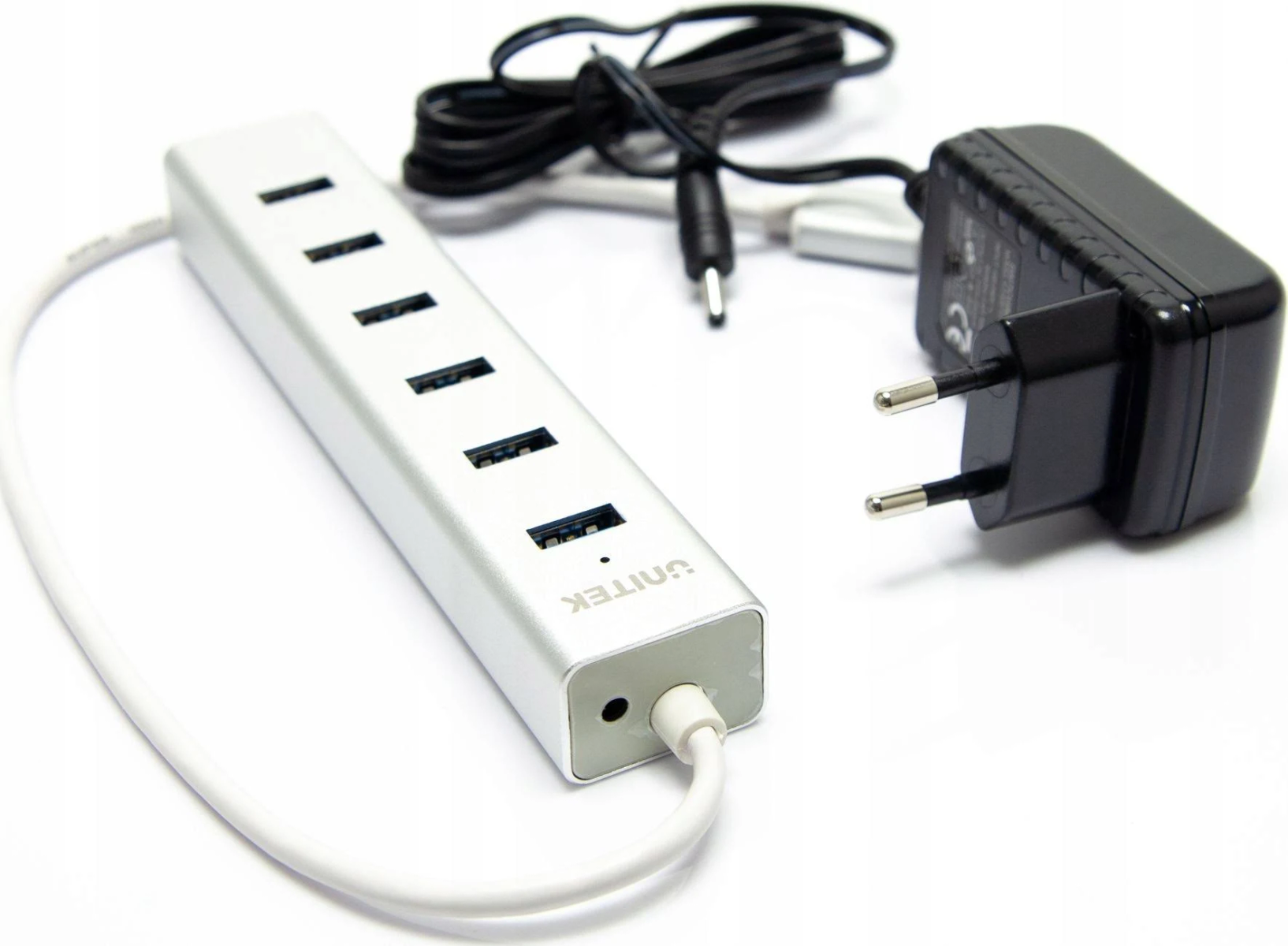 Silberner USB-Hub mit mehreren Anschlüssen, einem Netzteil und einem Ladekabel.