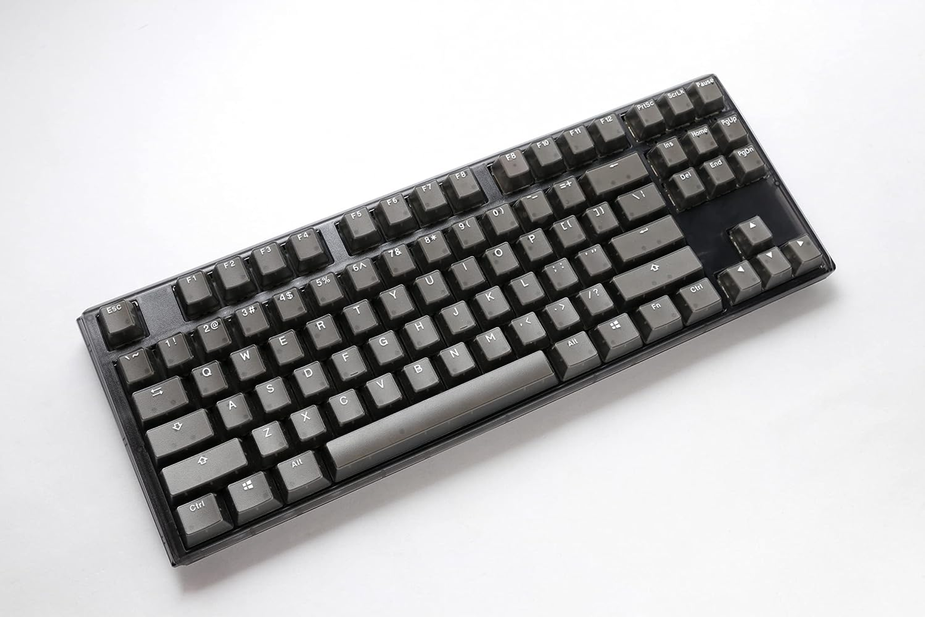 Een donkergrijs mechanisch toetsenbord op een witte ondergrond, met grijze keycaps.