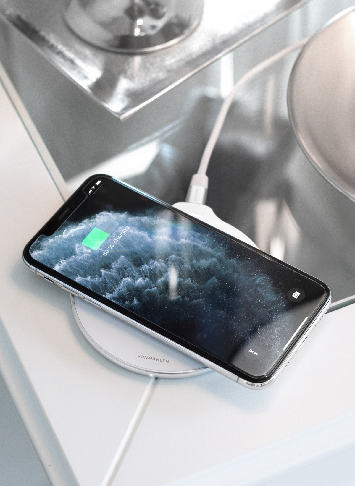 Ein Smartphone, das auf einem weißen kabellosen Ladegerät lädt, zeigt 60 % geladen an.