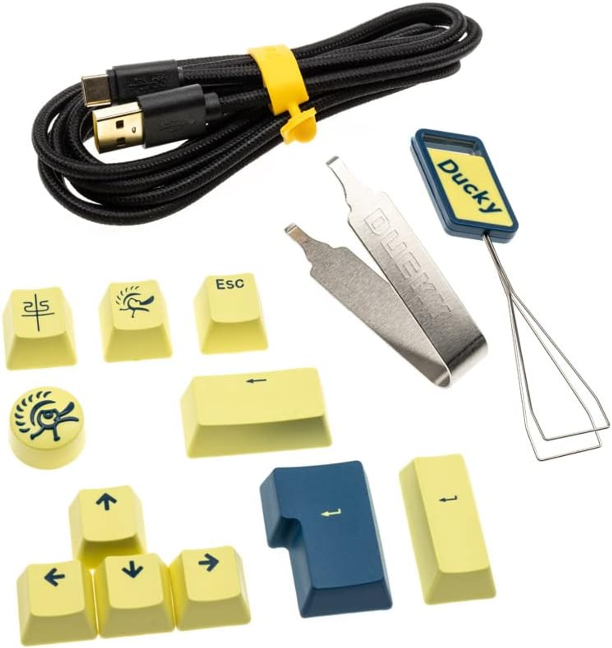 Accessori per tastiera: tasti, un cavo, un estrattore di tasti e pinzette. I tasti sono gialli con simboli.
