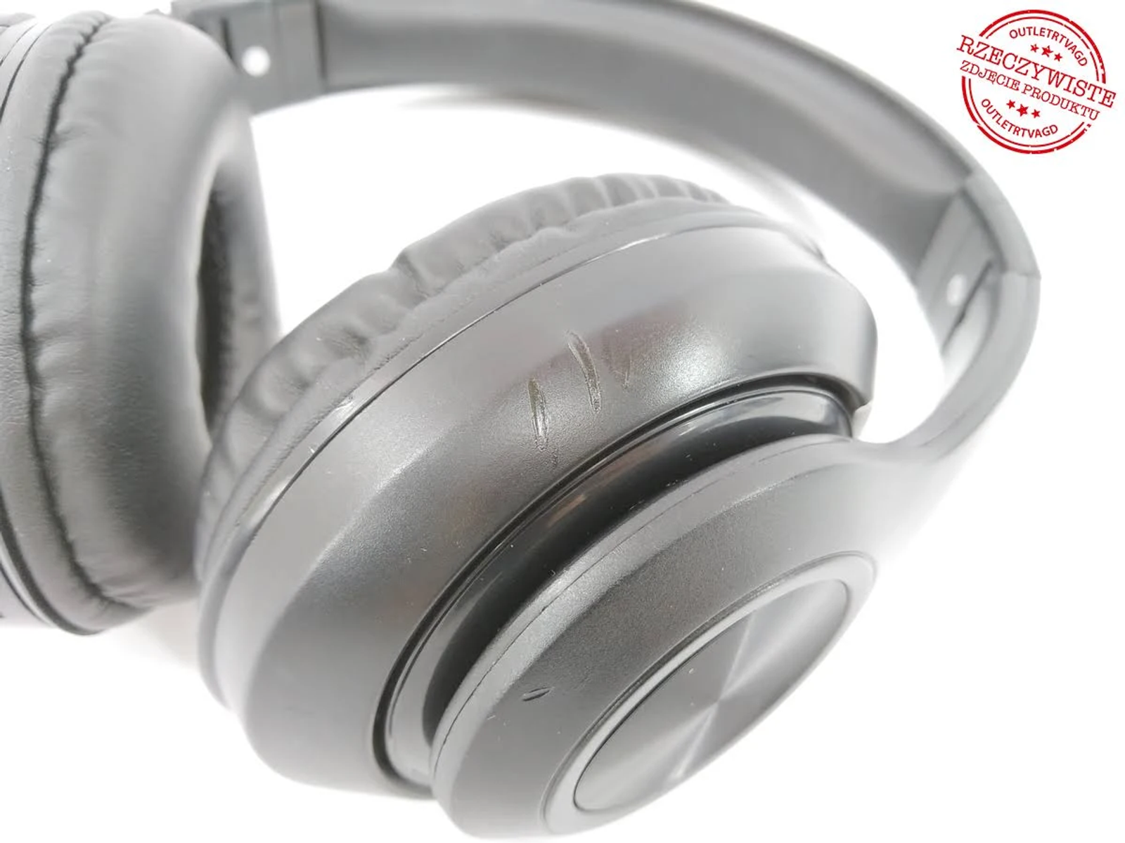 Czarne słuchawki, z kilkoma zadrapaniami, na białym tle. Zbliżenie na nauszniki.