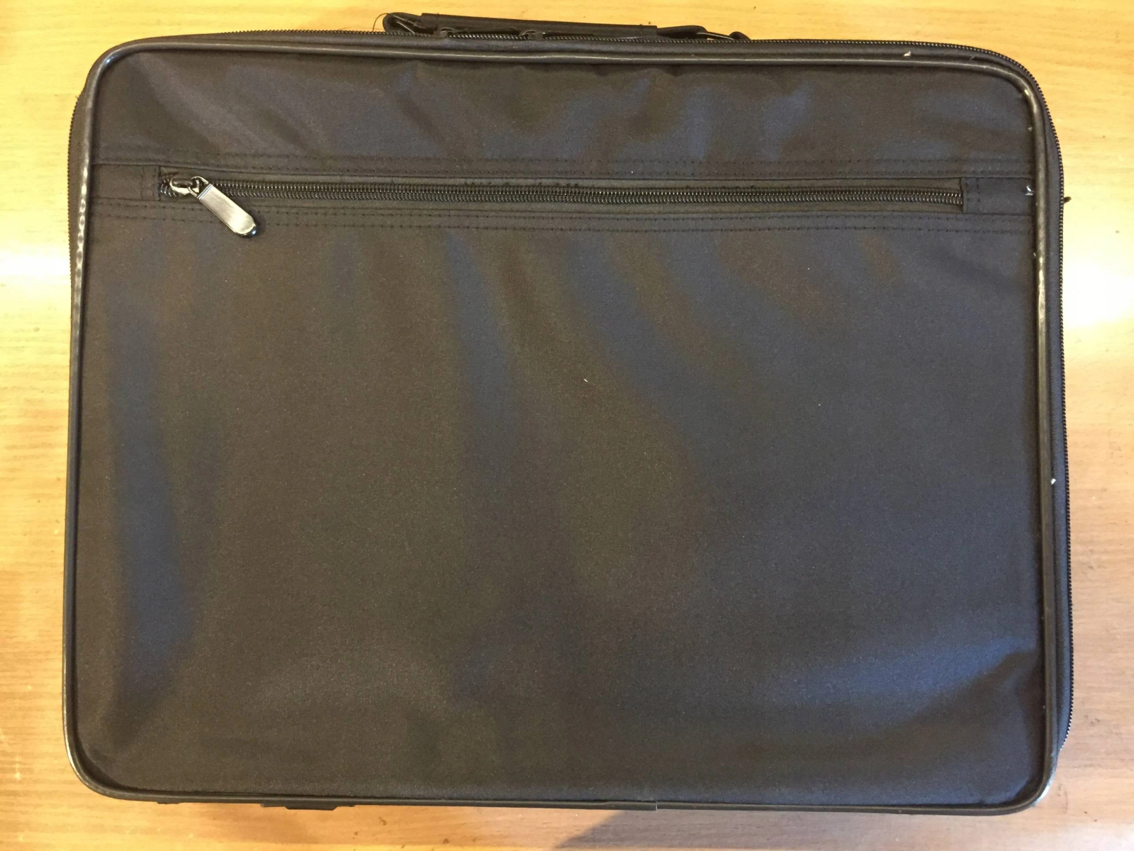Borsa per laptop nera con cerniera. Sfondo superficie in legno.