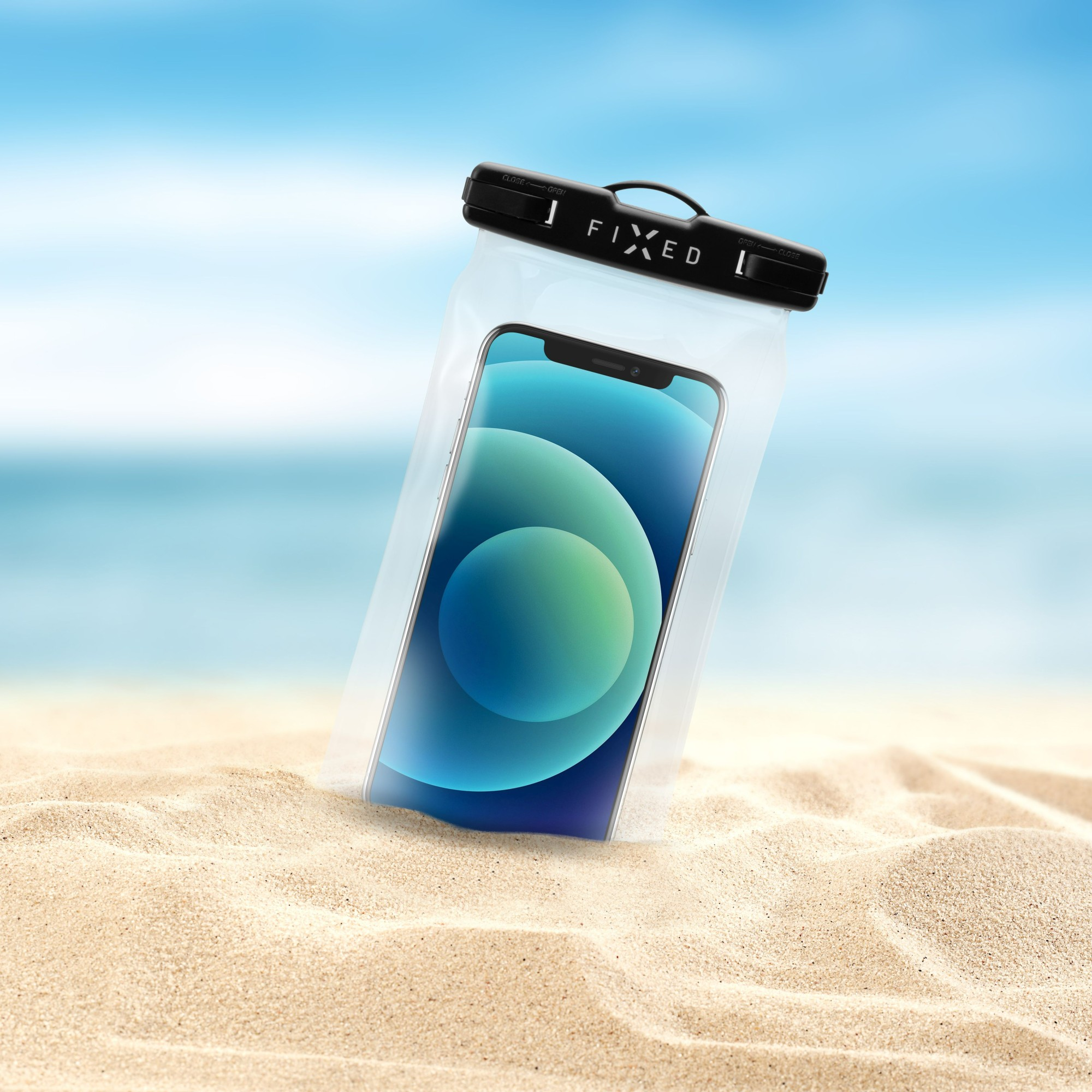 Ein Telefon in einer transparenten, wasserdichten Tasche am Strand. Die Tasche hat einen schwarzen Verschluss und einen Griff.