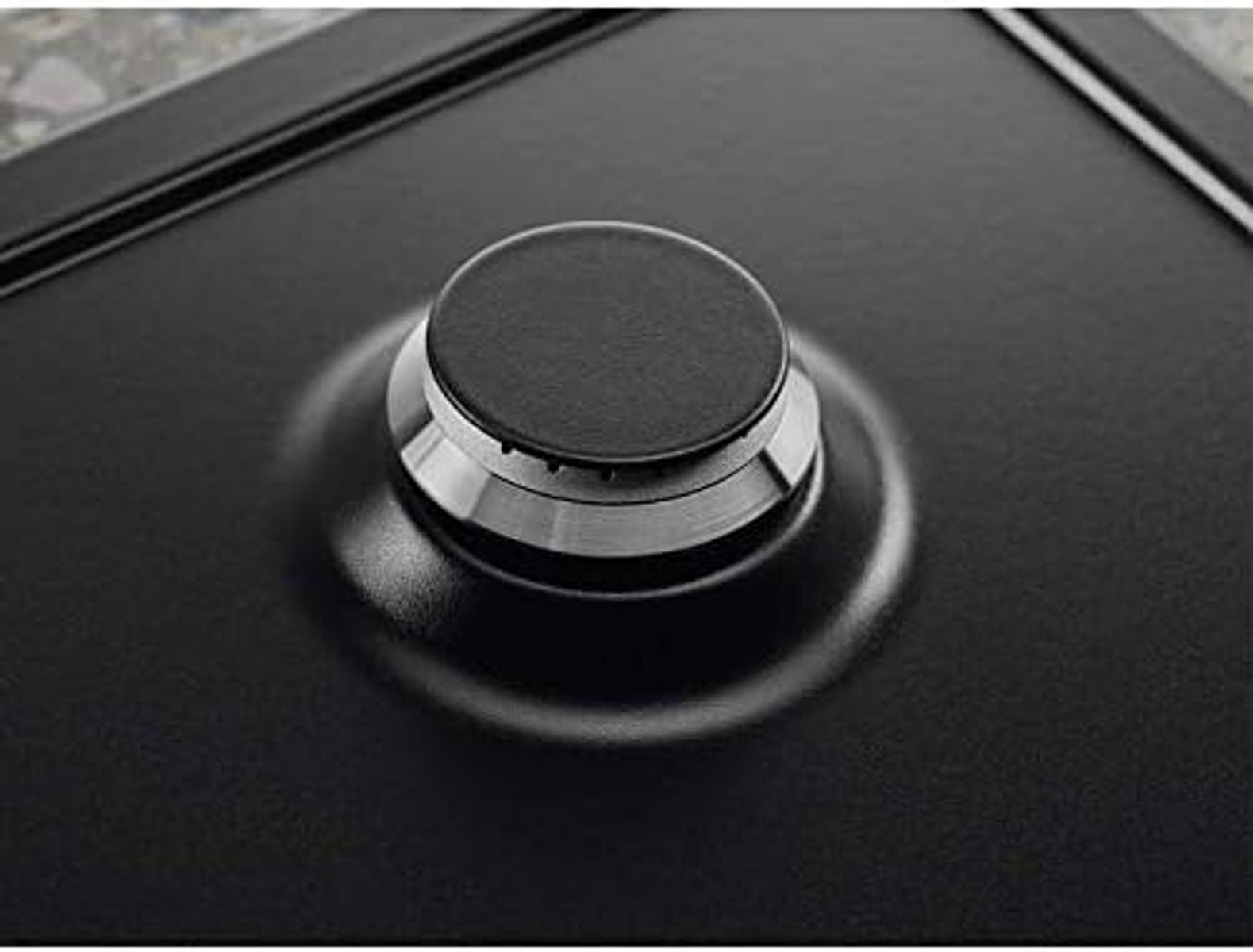 Zbliżenie czarnego pokrętła płyty grzewczej z srebrną podstawą.