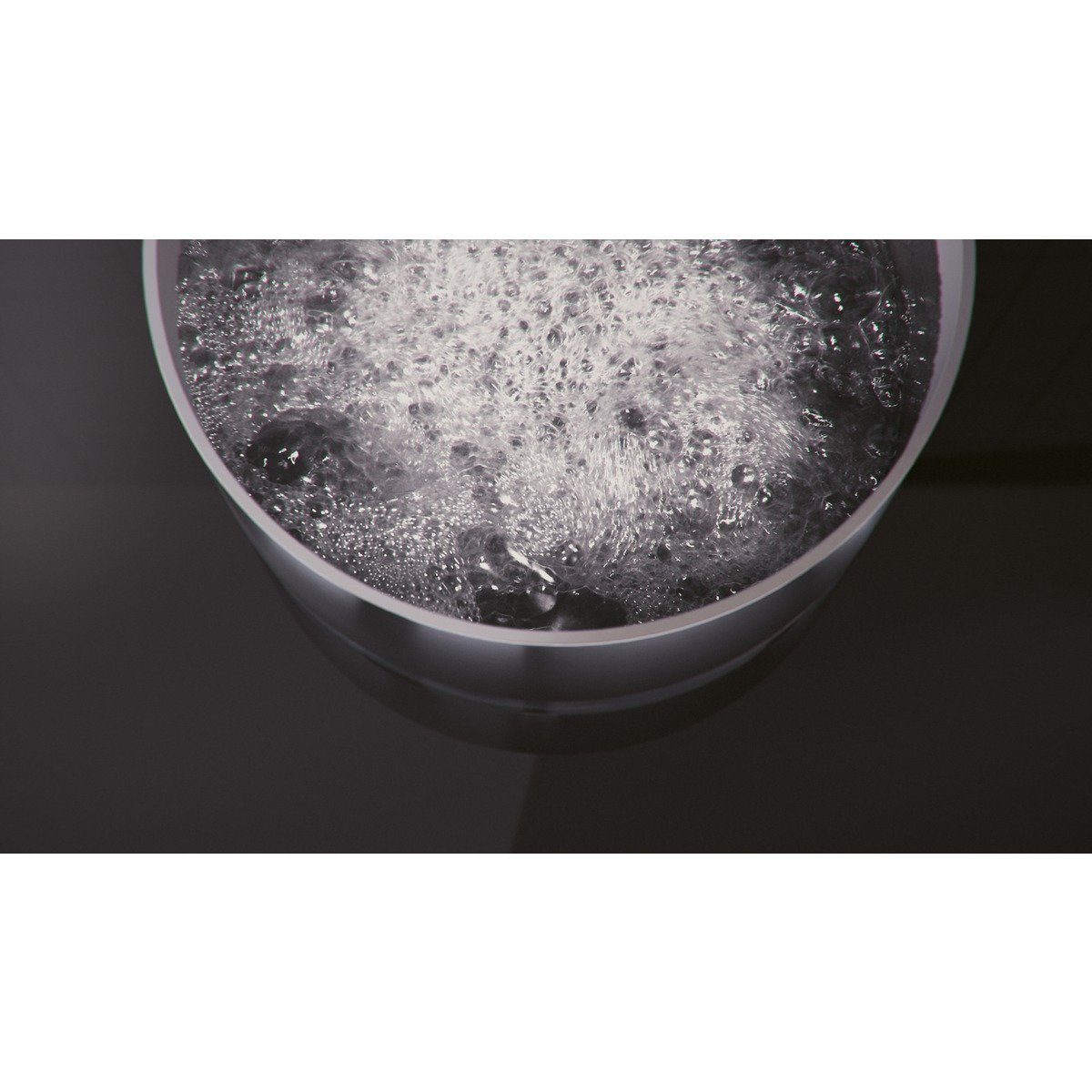 Bulgocząca woda w białym garnku. Garnek jest w ciemnym obszarze.