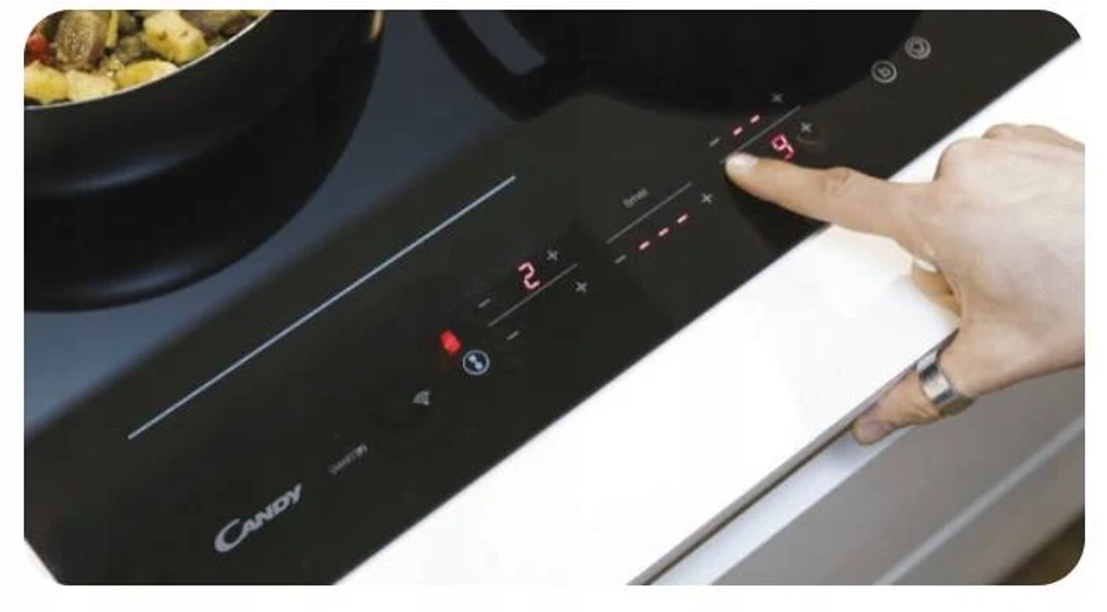 Dłoń dotykająca panelu sterowania. Marka Candy. Czarna powierzchnia.