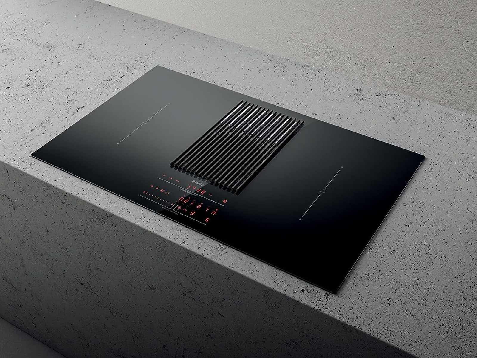 Una placa de inducción negra con ventilación integrada, sobre una superficie de hormigón.