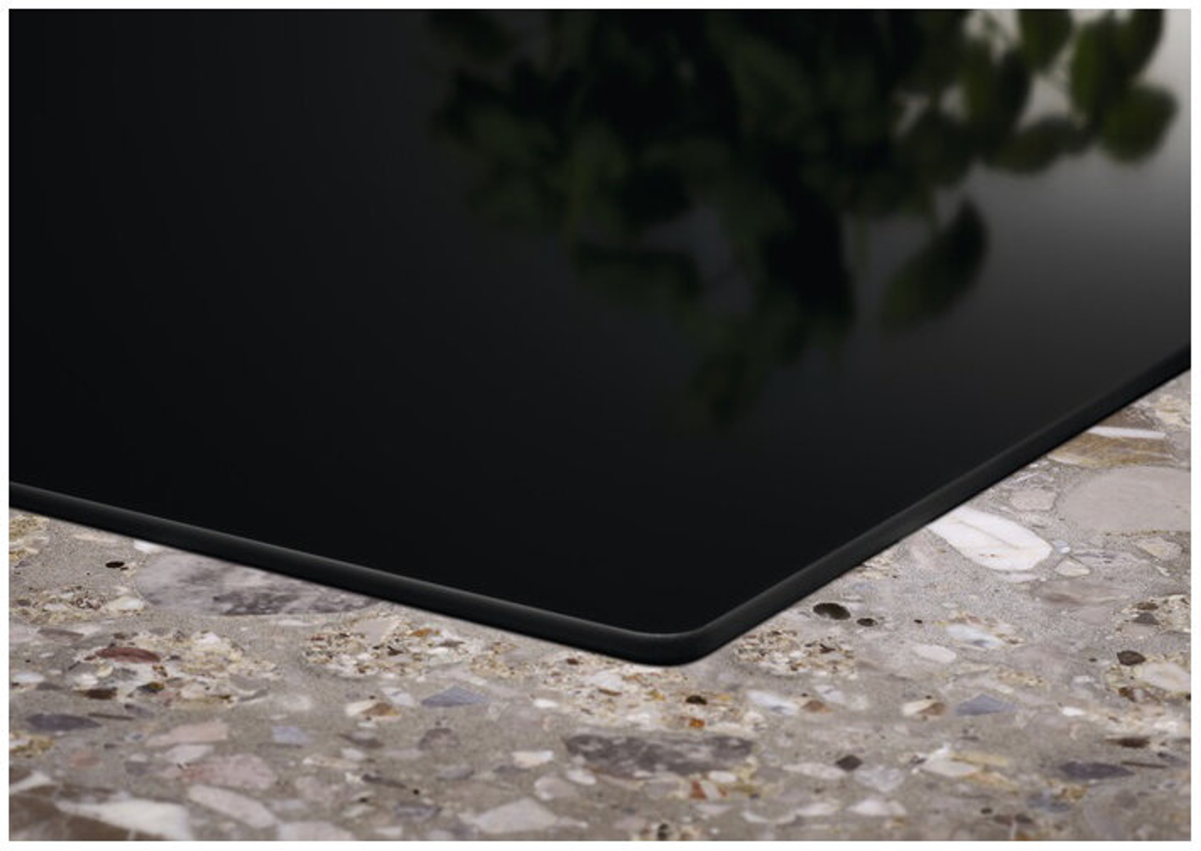 Zbliżenie na czarną powierzchnię płyty grzewczej. Gładka i odbijająca światło.