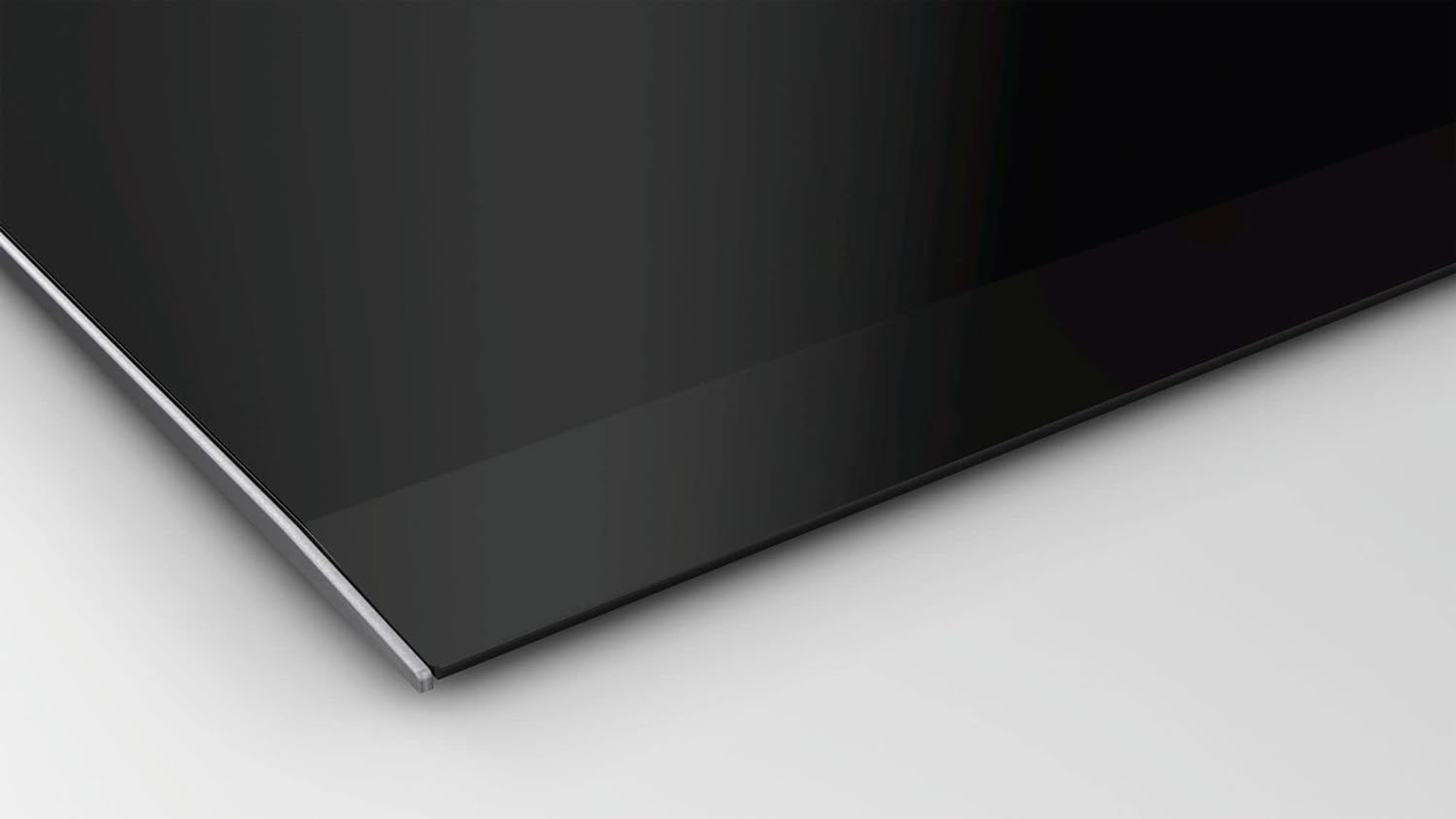 Close-up of a black hob corner with a silver edge.