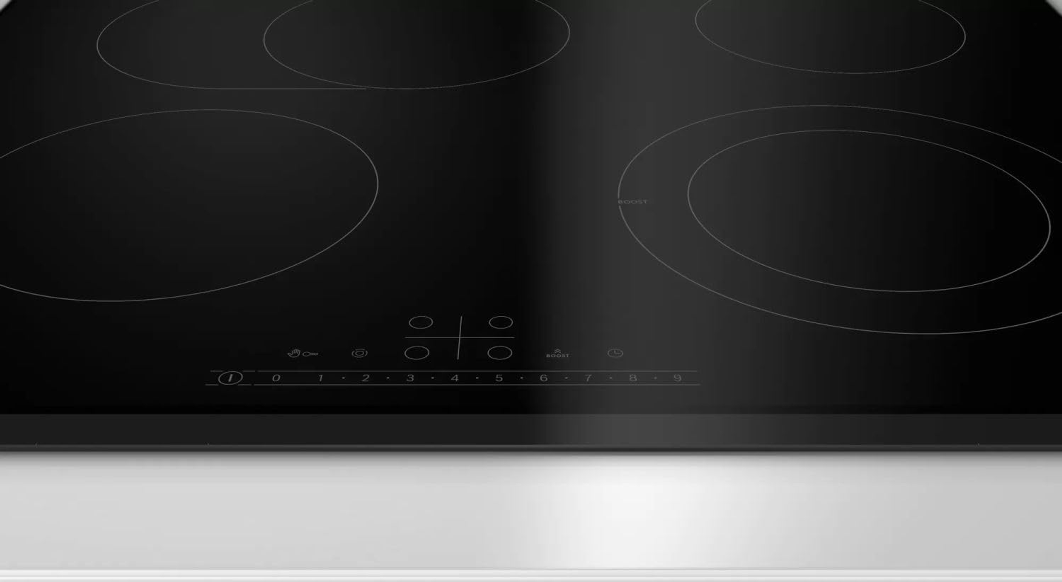 Czarna płyta indukcyjna. Cztery okrągłe palniki. Biała podstawa.