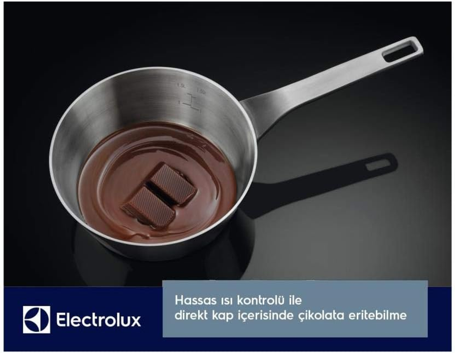 Garnek ze stali nierdzewnej z roztopioną czekoladą. Czarna powierzchnia. Logo i tekst Electrolux.