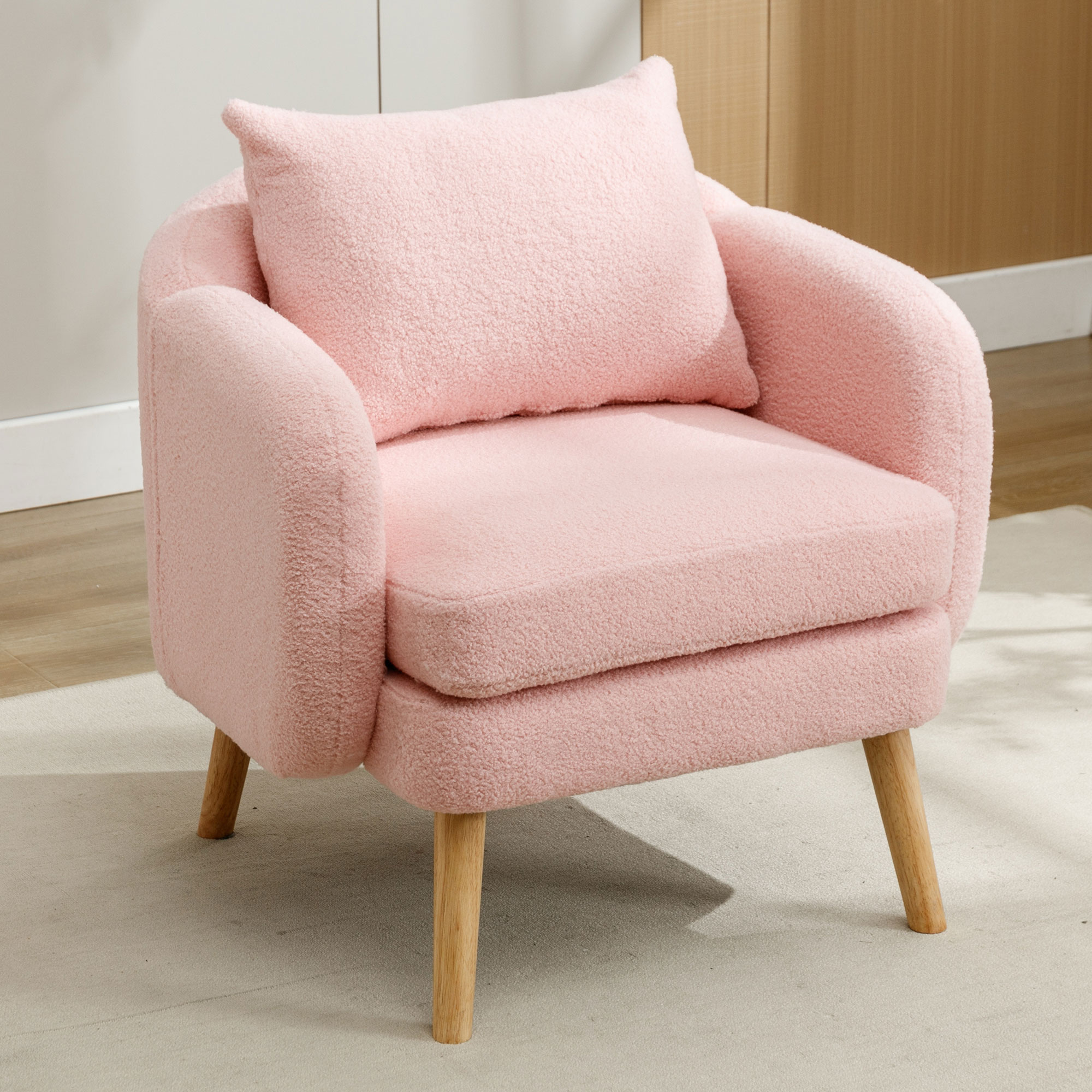 Rosa Teddybär-Sessel mit Holzbeinen und passendem Kissen. Der Hintergrund ist neutral.