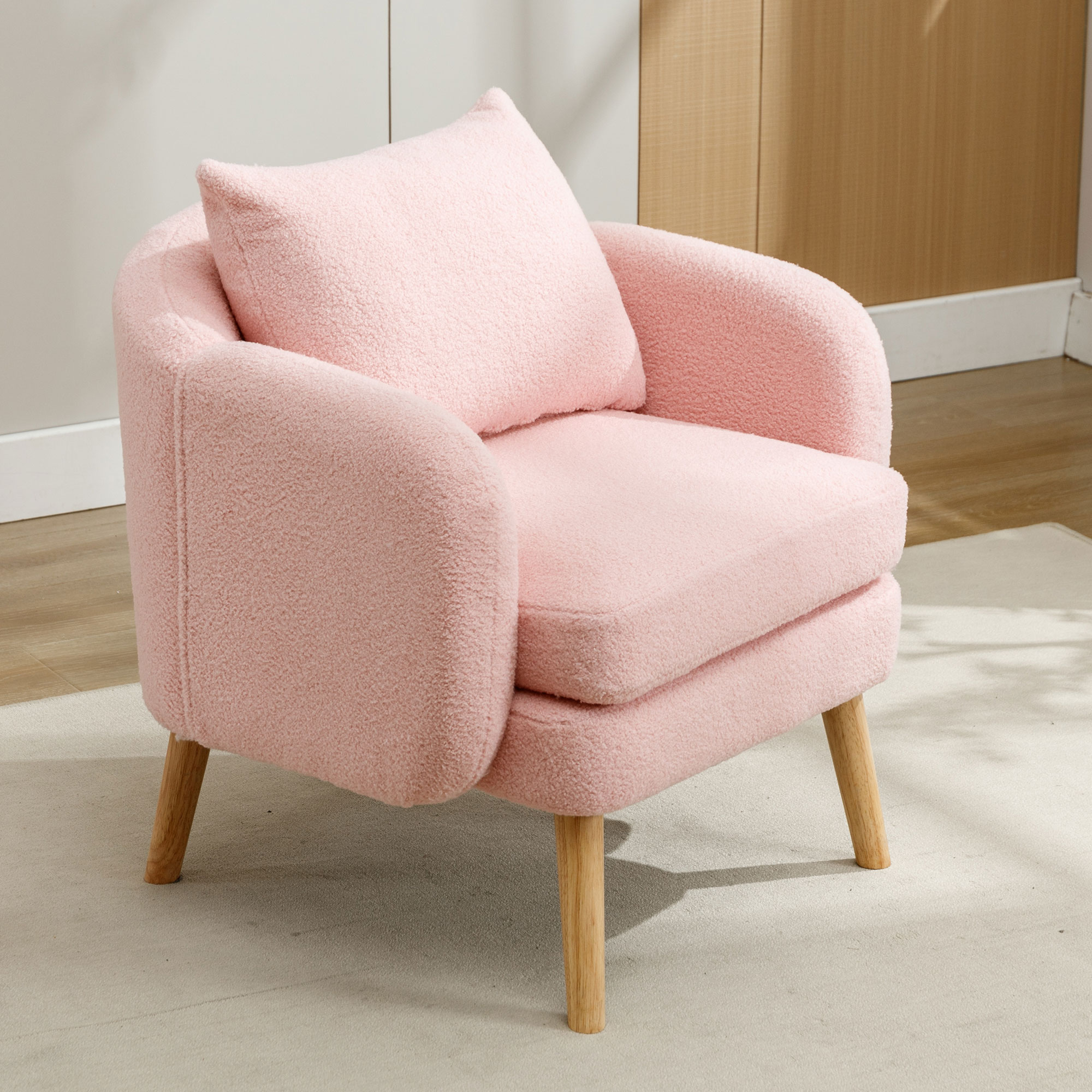 Ein rosa, plüschiger Sessel mit Kissen. Steht auf hellem Teppich. Holzbeine vorhanden.