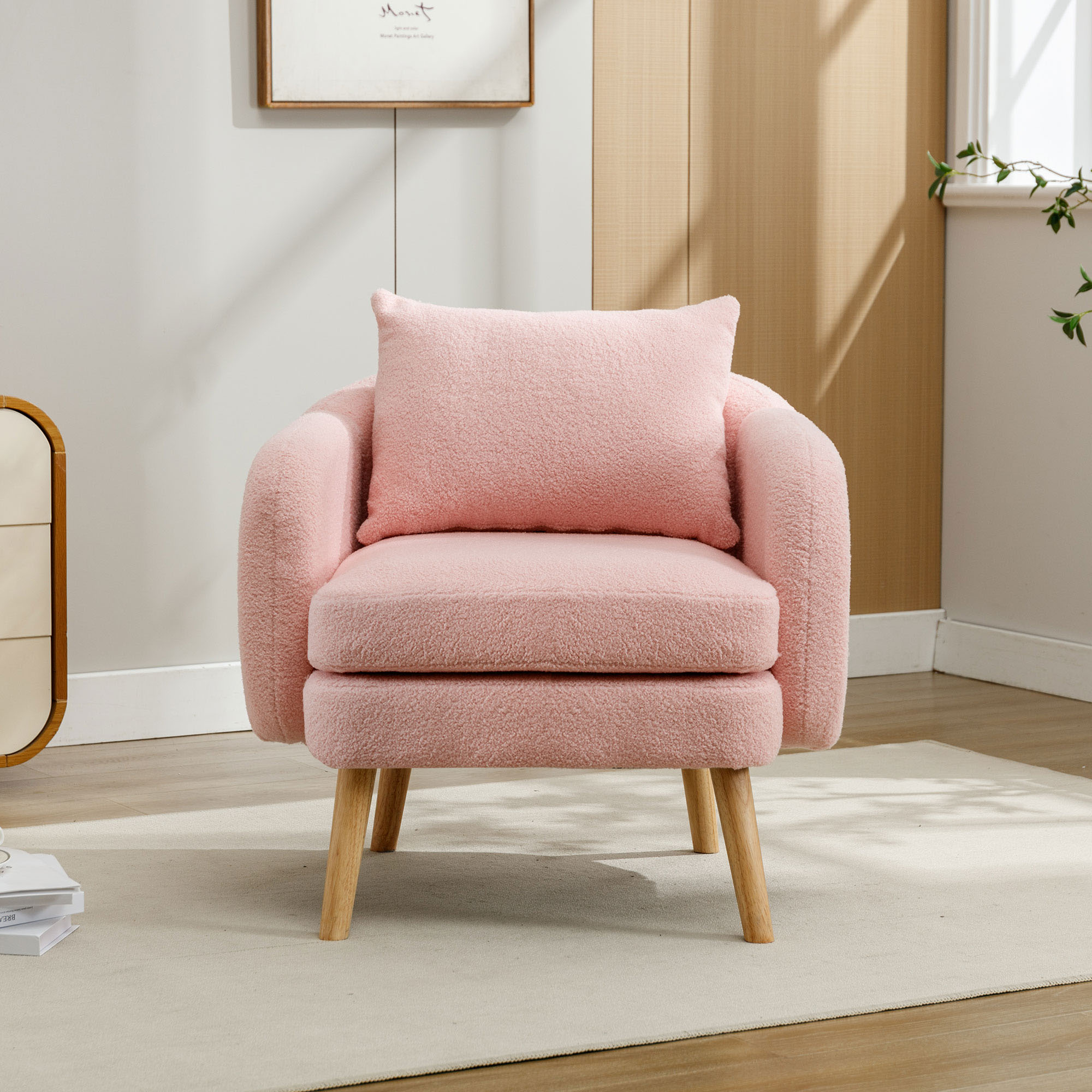 Ein rosa Sessel mit passendem Kissen steht auf einem Teppich in einem Raum mit Holzboden und beigen Wänden.
