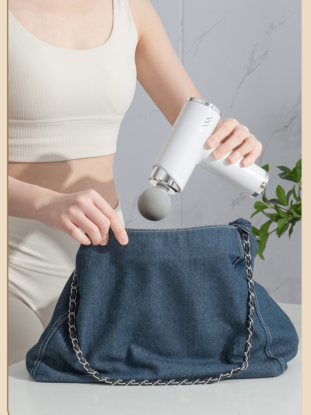 Eine Frau, die eine Massagepistole in eine blaue Jeans-Tasche legt.
