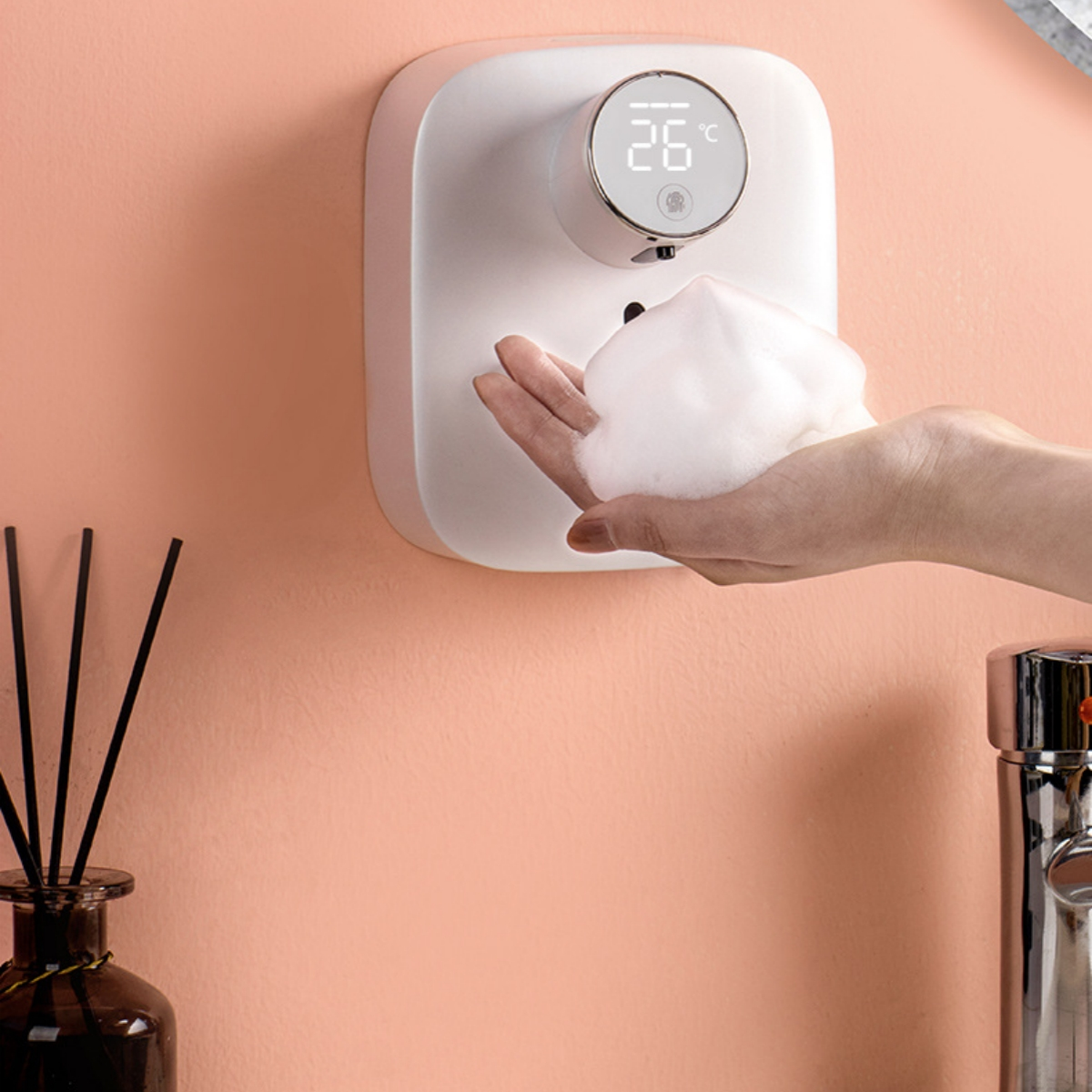 Weißer Seifenspender mit Hand, die Schaum empfängt, vor rosa Wand.