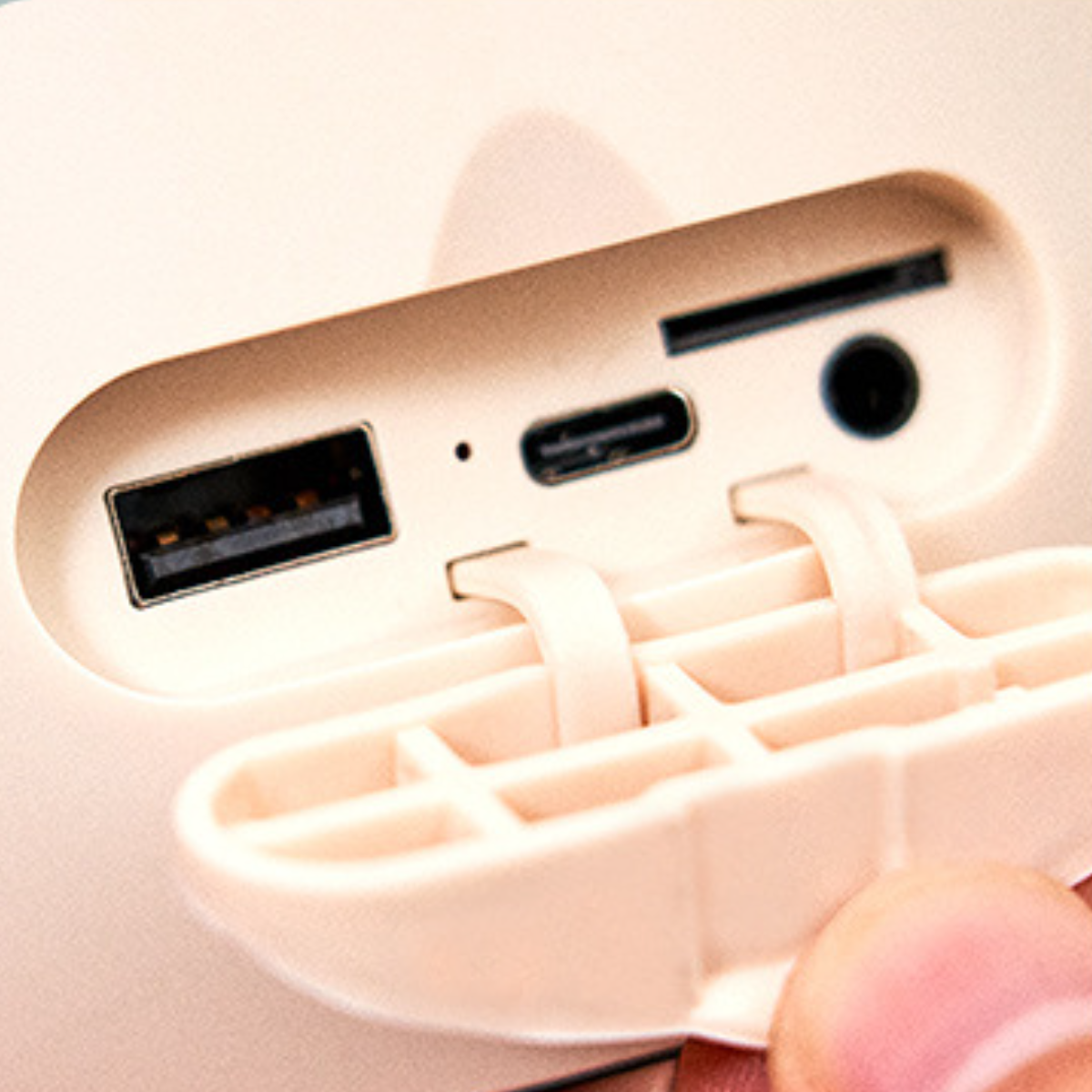 Nahaufnahme einer weißen und cremefarbenen Powerbank mit verschiedenen Anschlüssen und einer Kunststoffabdeckung.