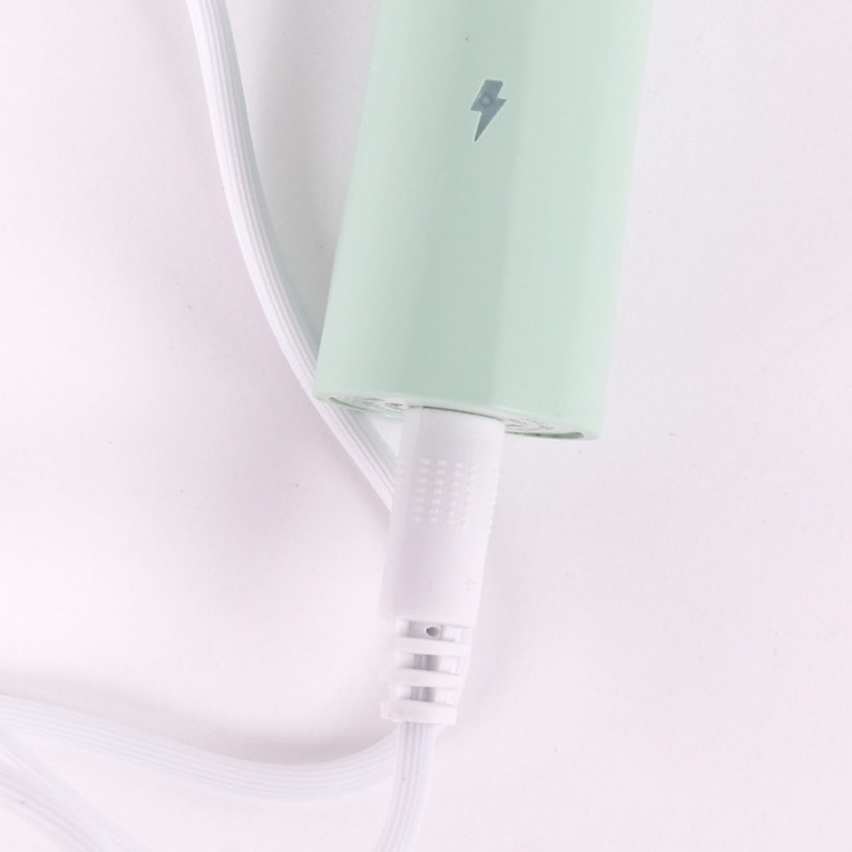 Nahaufnahme eines Ladeanschlusses eines mintgrünen Geräts mit weißem Kabel.