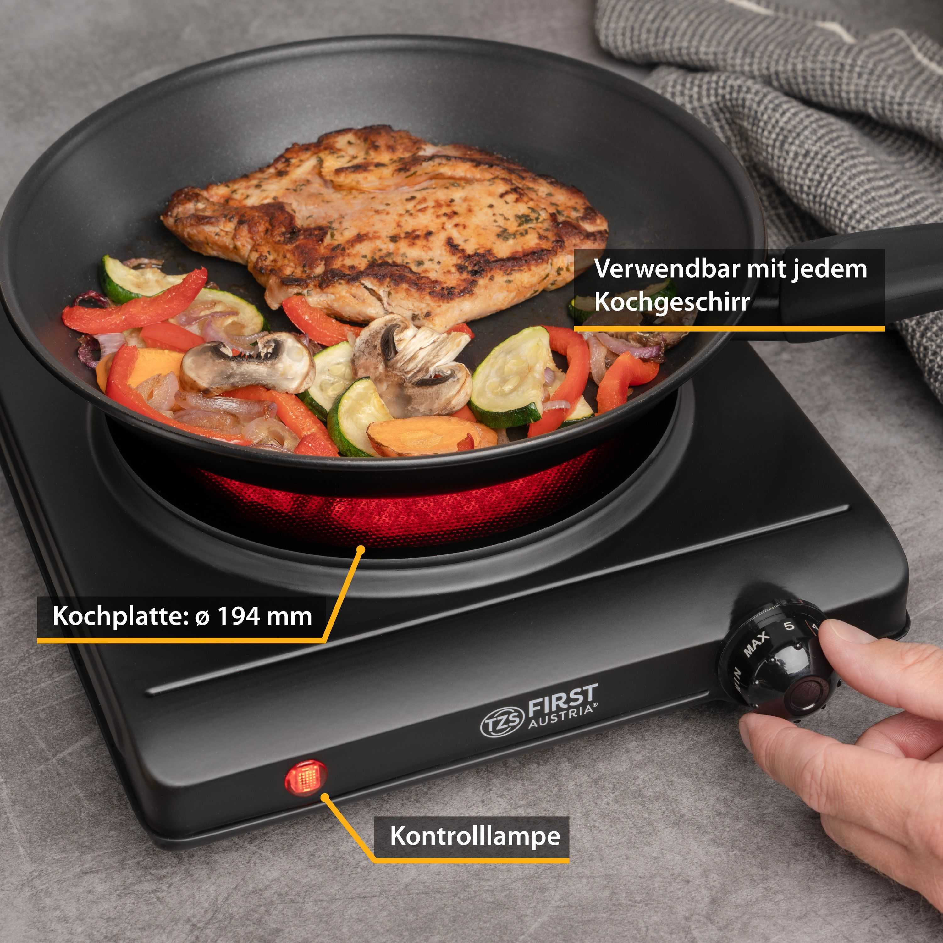 Schwarze elektrische Kochplatte mit Essen. Eine Hand stellt das Hitzegrad ein.