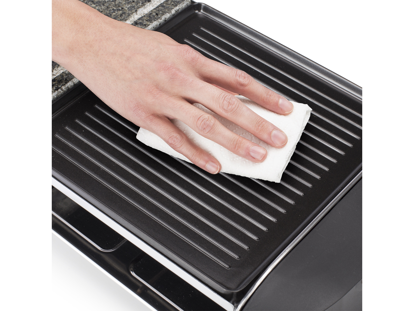 Eine Hand reinigt einen schwarzen Grill mit einem weißen Tuch. Der Grill befindet sich auf einem schwarzen und silbernen Gerät.