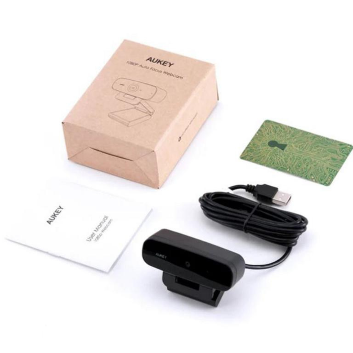 AUKEY Webcam und Box mit Karte und Handbuch. Alle Artikel auf weißer Oberfläche, hohe Winkele.