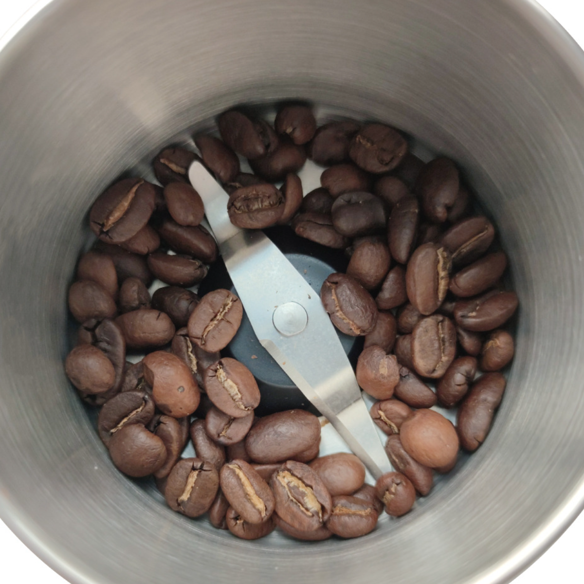 Kaffeebohnen in einer Kaffeemühle mit Klinge.
