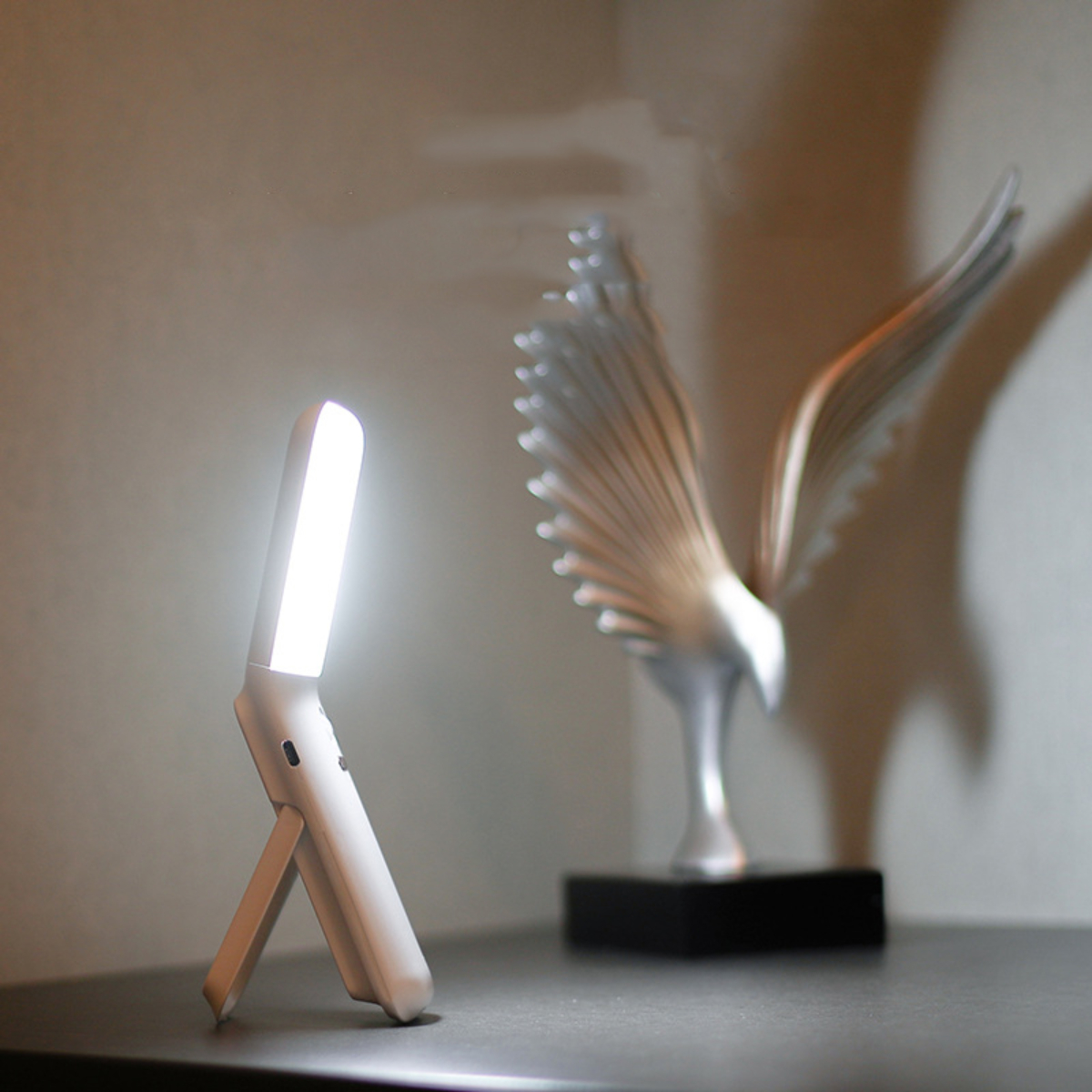 Weißes Licht mit Ständer auf dem Tisch, silberne Adlerstatue im Hintergrund.