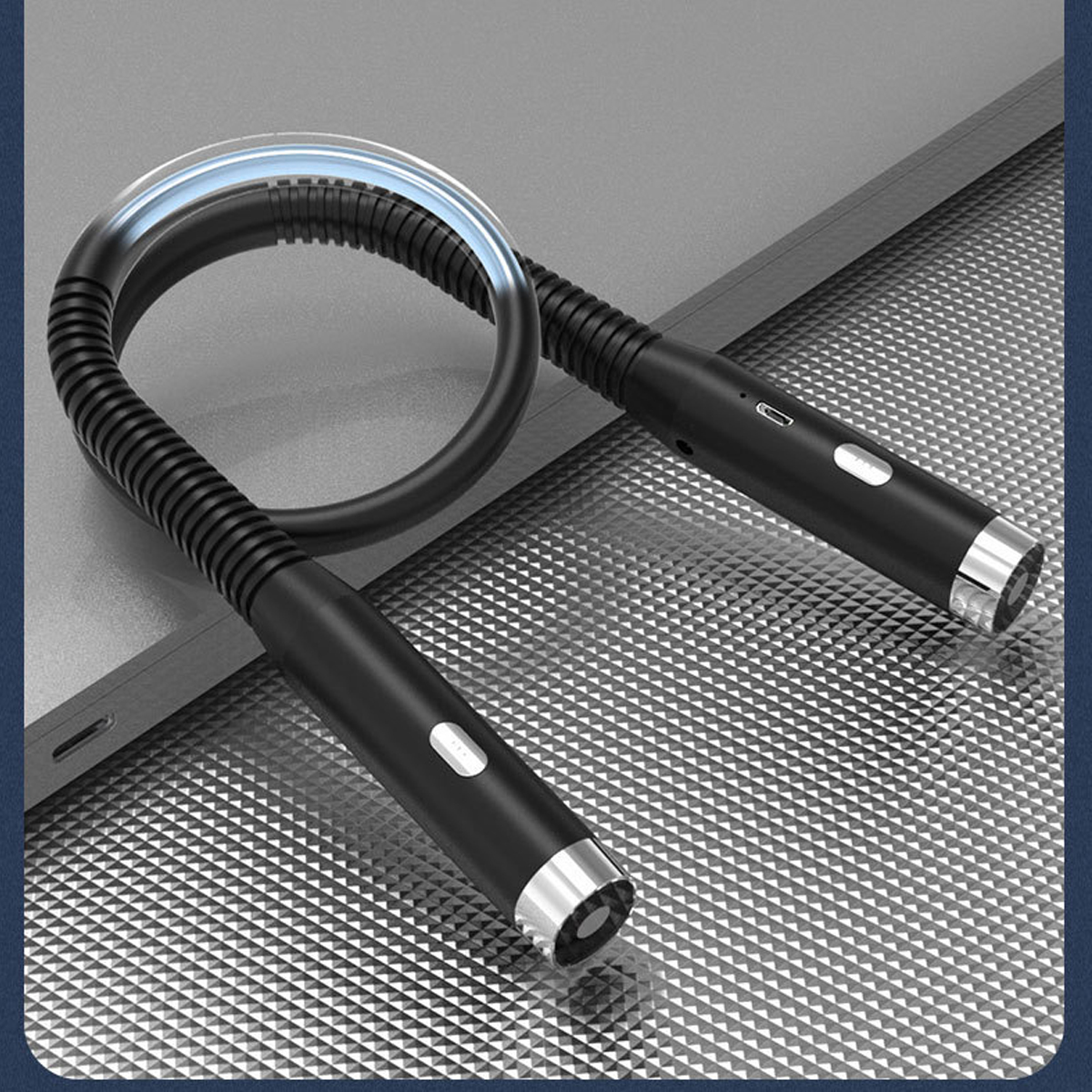 Eine flexible schwarze LED-Schreibtischlampe auf einer silbernen Oberfläche. Sie hat einen USB-Ladeanschluss.
