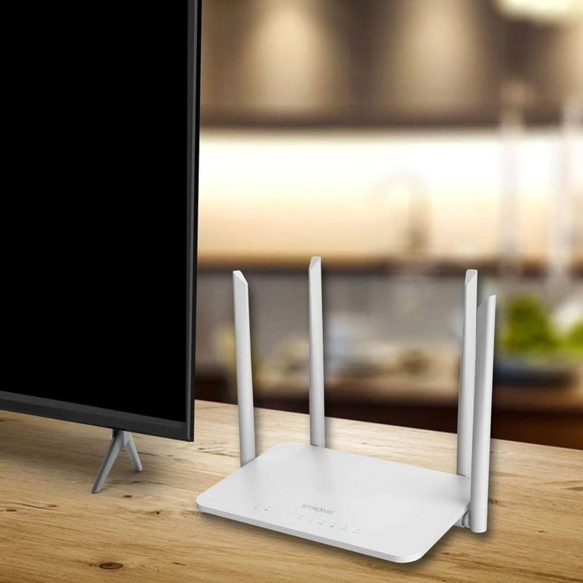 Router bianco con antenne, vicino a un televisore su un tavolo di legno.