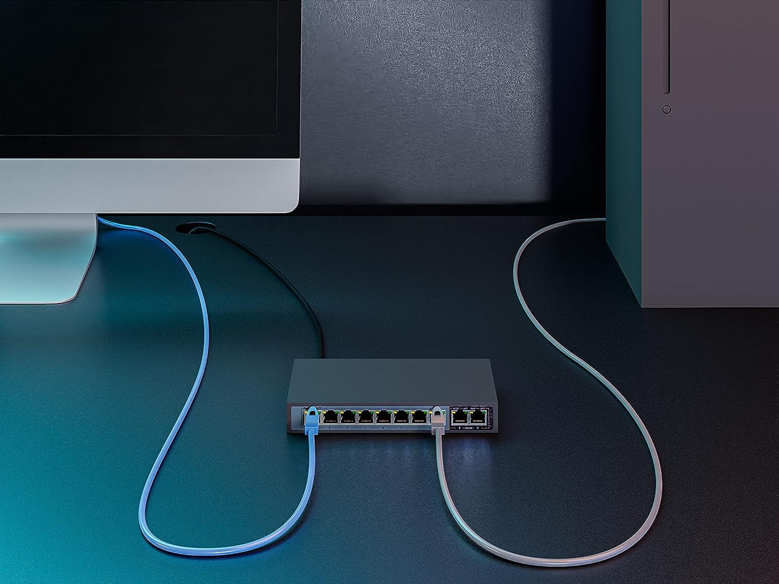 Uno switch nero collegato a un computer e a un monitor, con cavi blu.