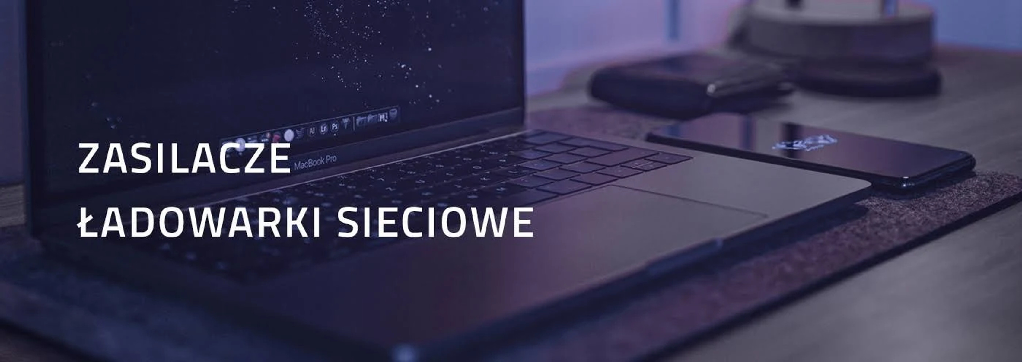 Ein Laptop und ein Smartphone auf einem Holzschreibtisch, mit Text auf Polnisch: Ladegeräte, Netzteile.