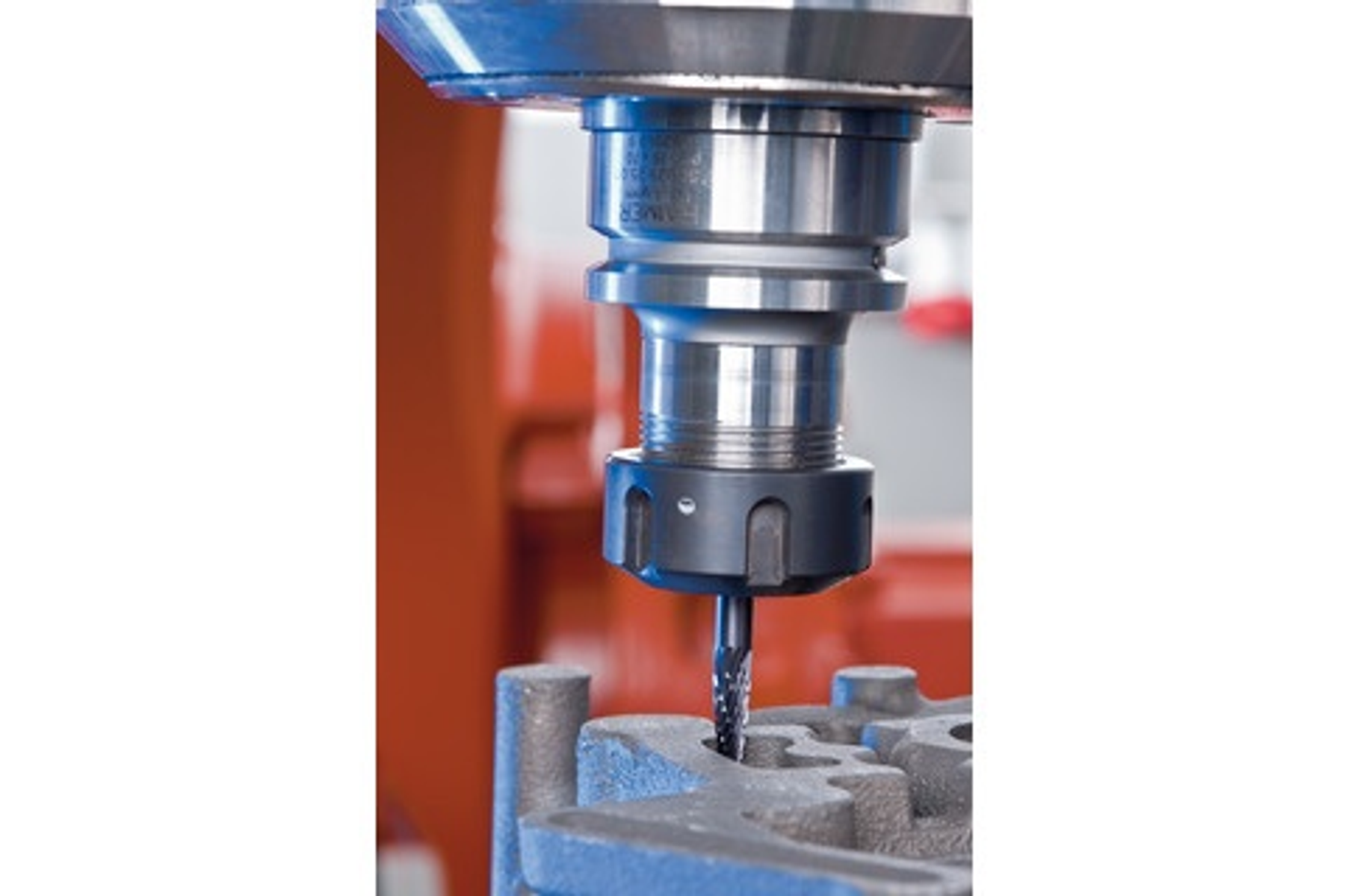 Ein Metallfräswerkzeug schneidet in ein Metallteil. Das Werkzeug ist silberfarben, das Teil grau.