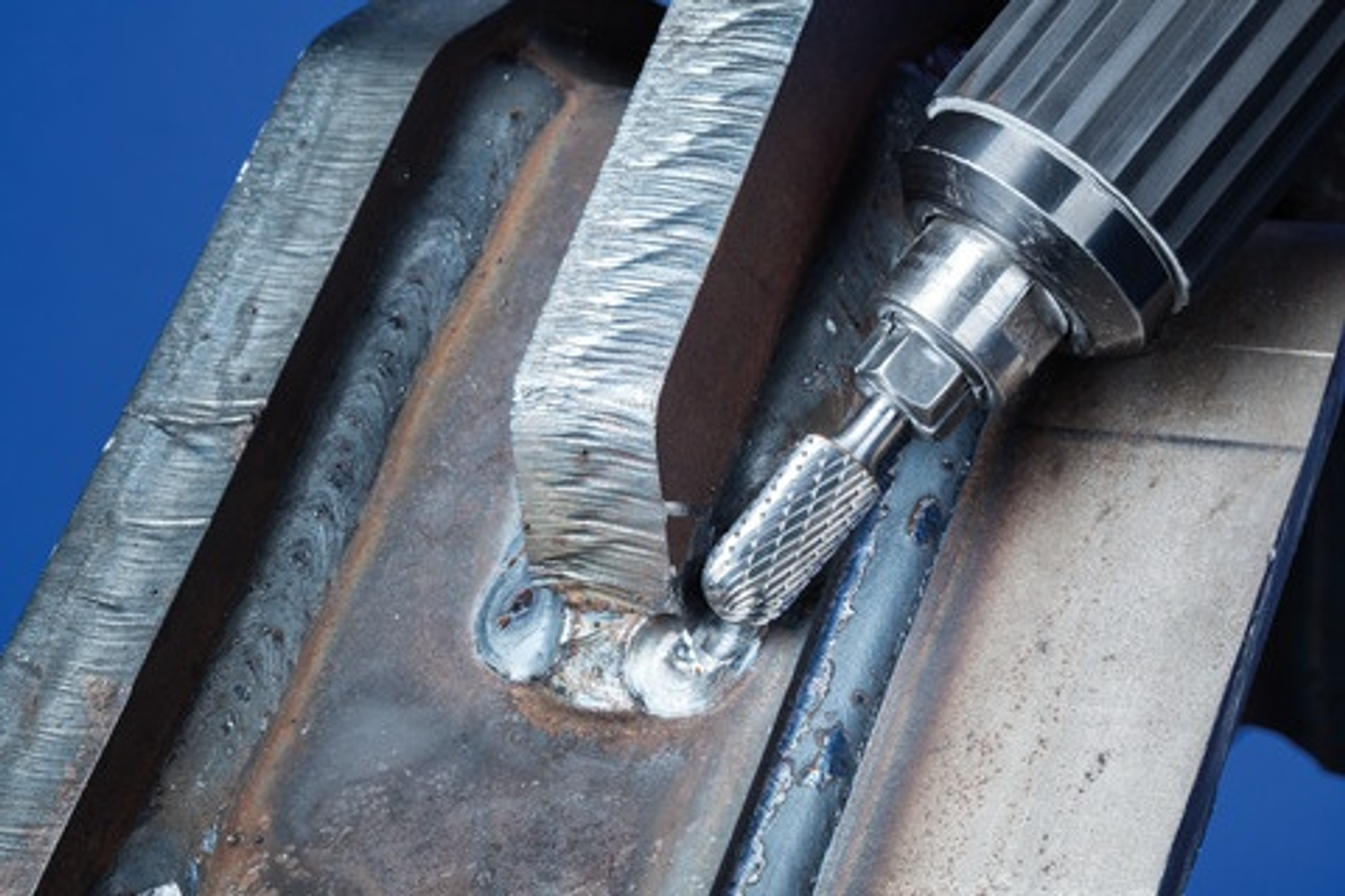 Nahaufnahme eines Metallstücks, das von einem Werkzeug geschliffen wird. Funken fliegen vom Schleifen ab.