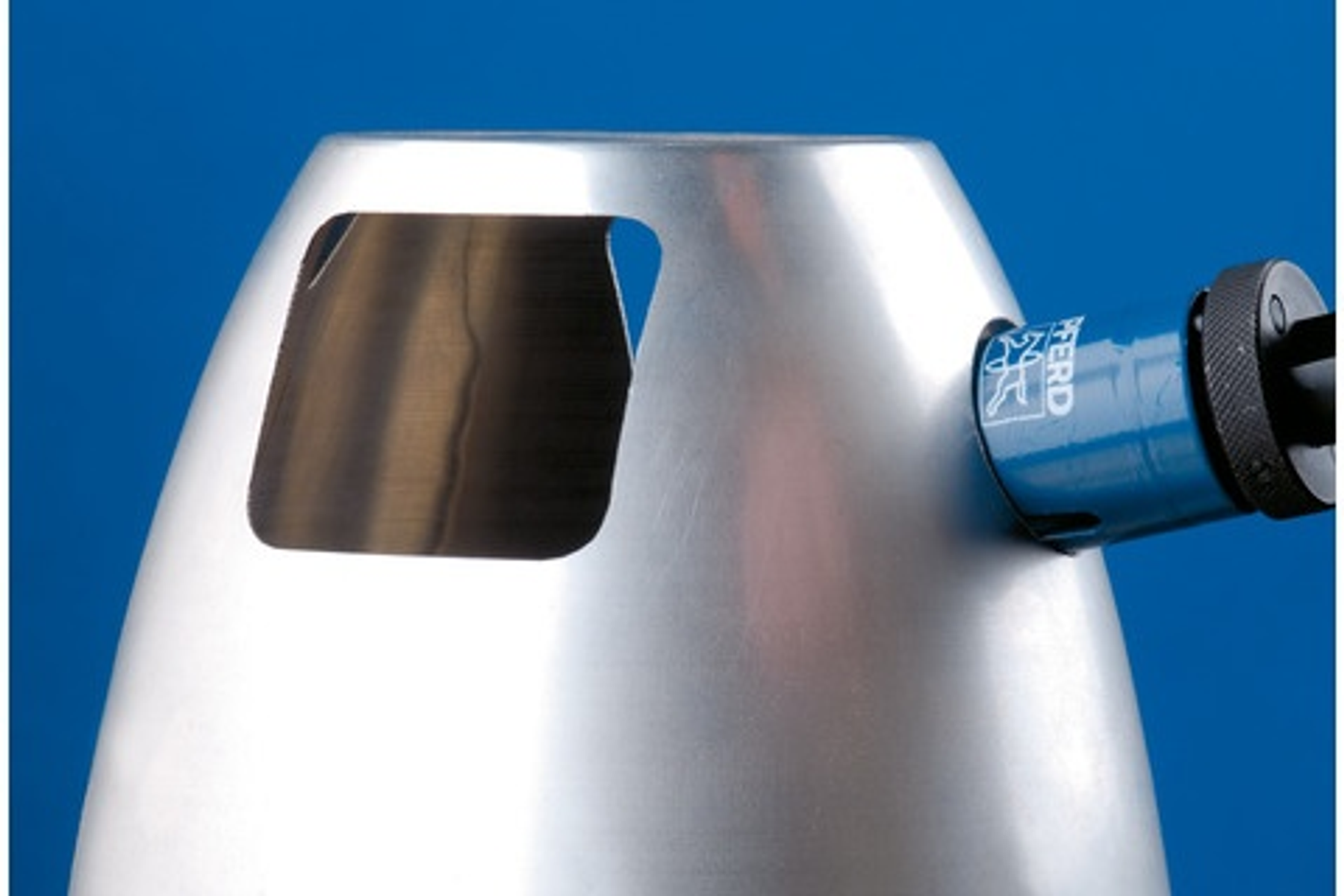 Ein silbernes Metallobjekt mit einem Ausschnitt wird gezeigt, in das ein blaues Werkzeug eingesetzt ist.