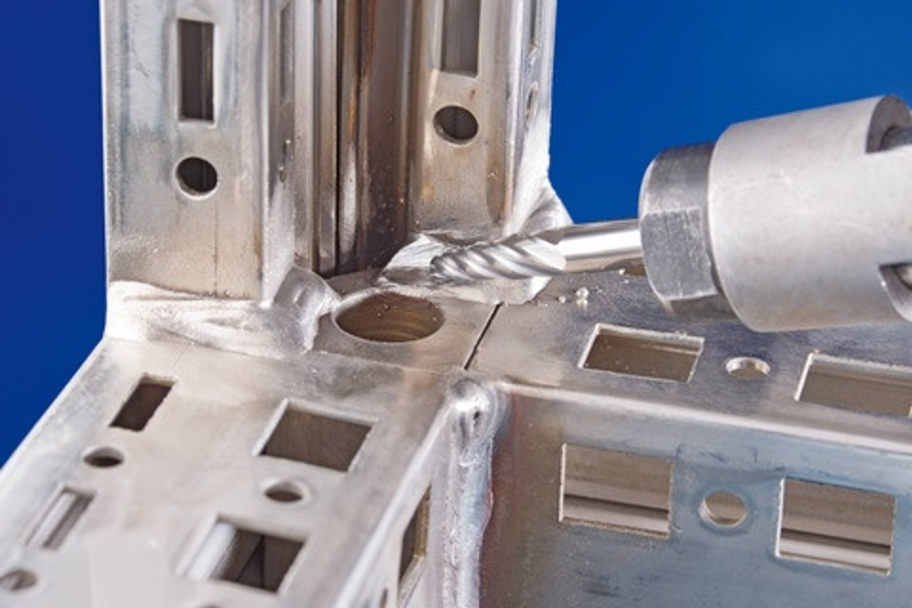 Ein Werkzeug schleift eine Metallkonstruktion. Funken fliegen vom Kontaktpunkt ab.
