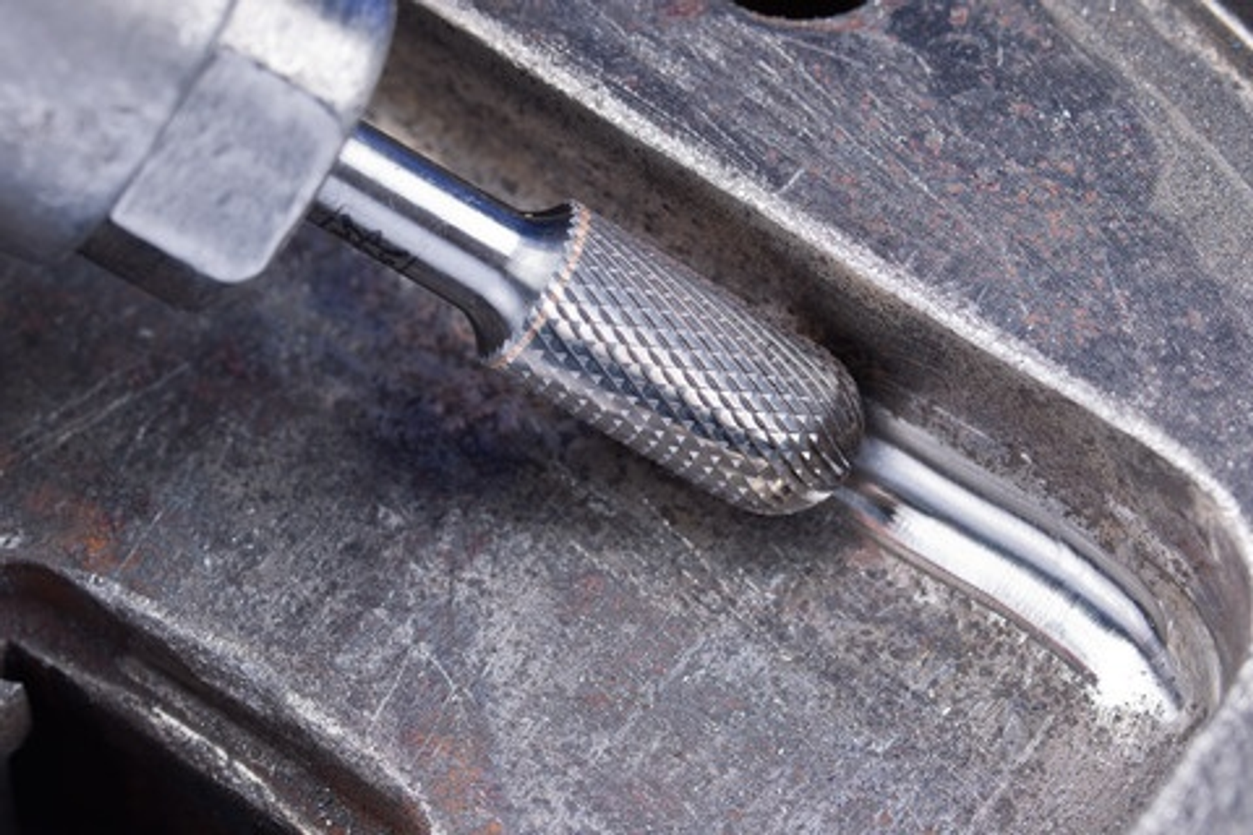 Ein Werkzeug schleift eine Metalloberfläche. Funken sind vom Kontaktpunkt aus sichtbar.