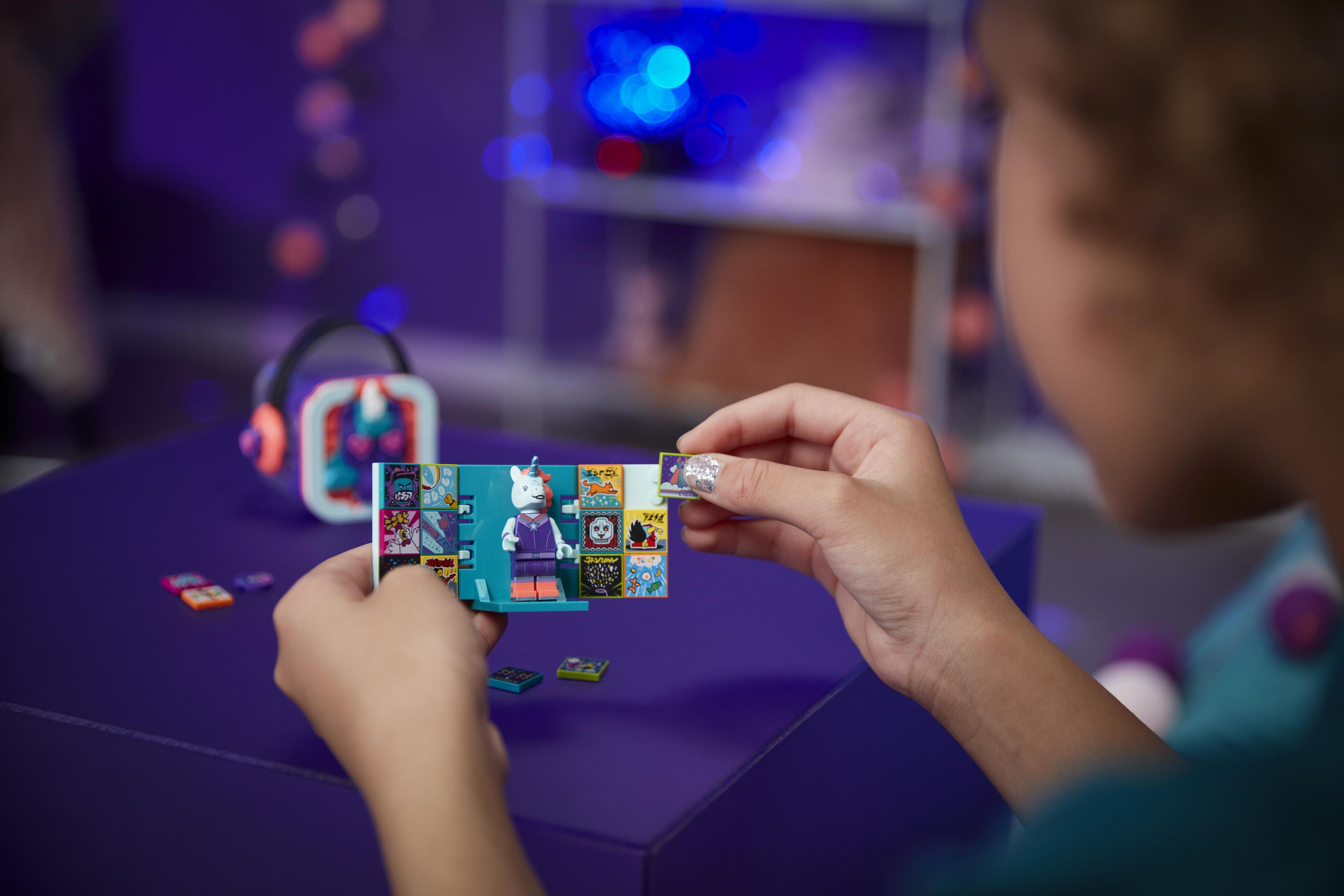 Osoba trzyma książkę Lego. Kot Lego jest na otwartej stronie, w pobliżu naklejki.