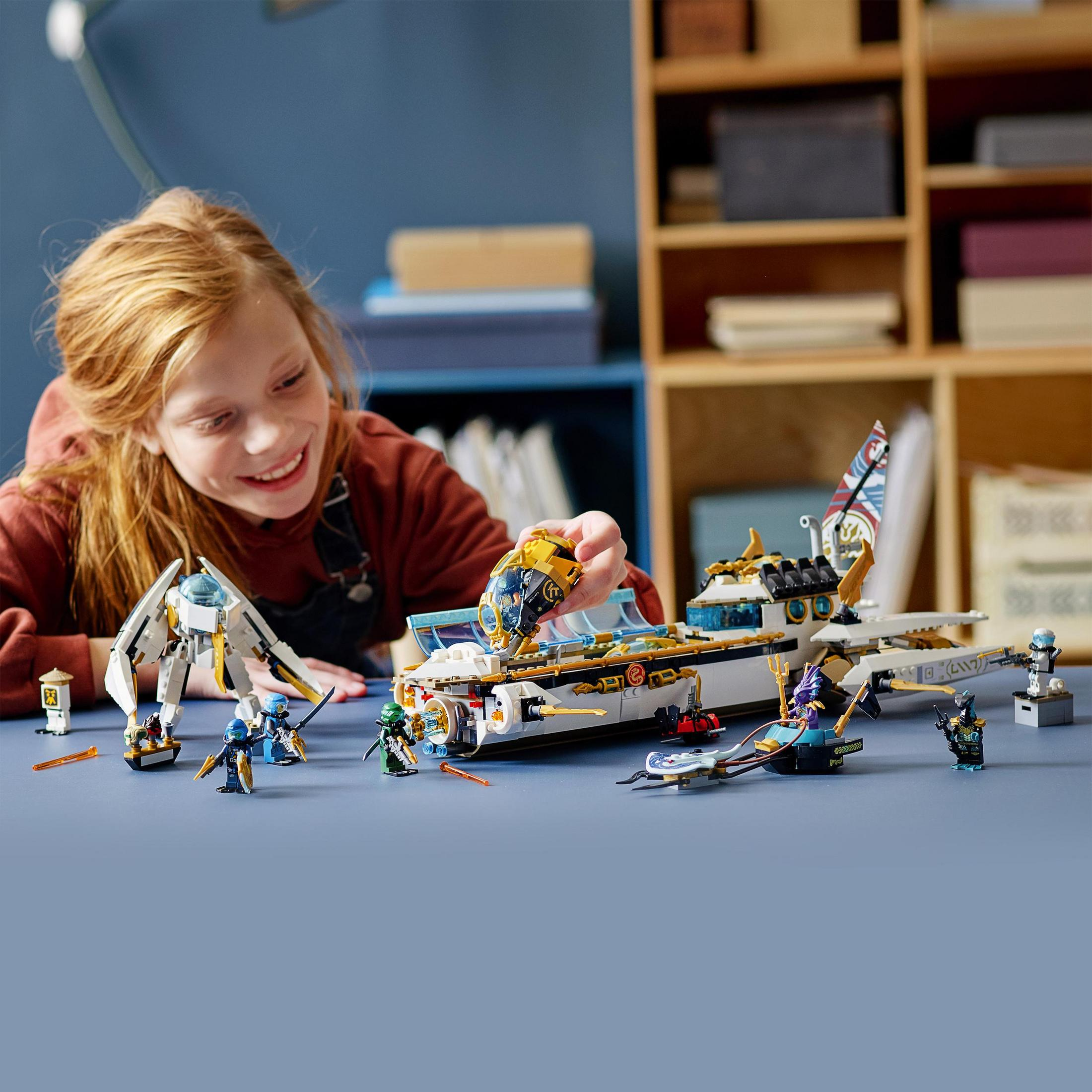 Une fille joue avec un set LEGO. L'ensemble comprend un bateau et plusieurs figurines.