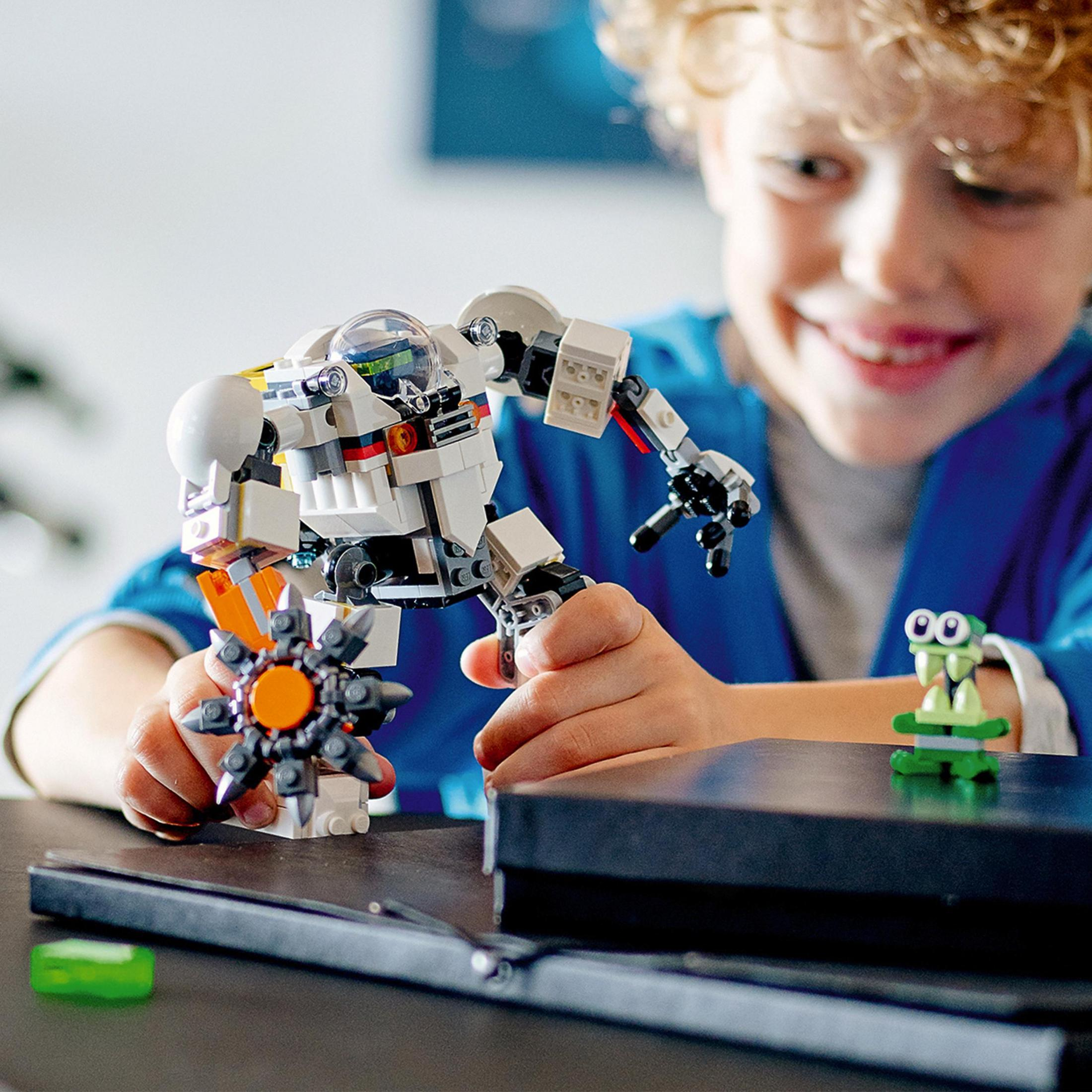 Ein Junge spielt mit einem weißen Roboter-Spielzeug mit orangefarbenen und grauen Teilen. Der Hintergrund ist verschwommen.
