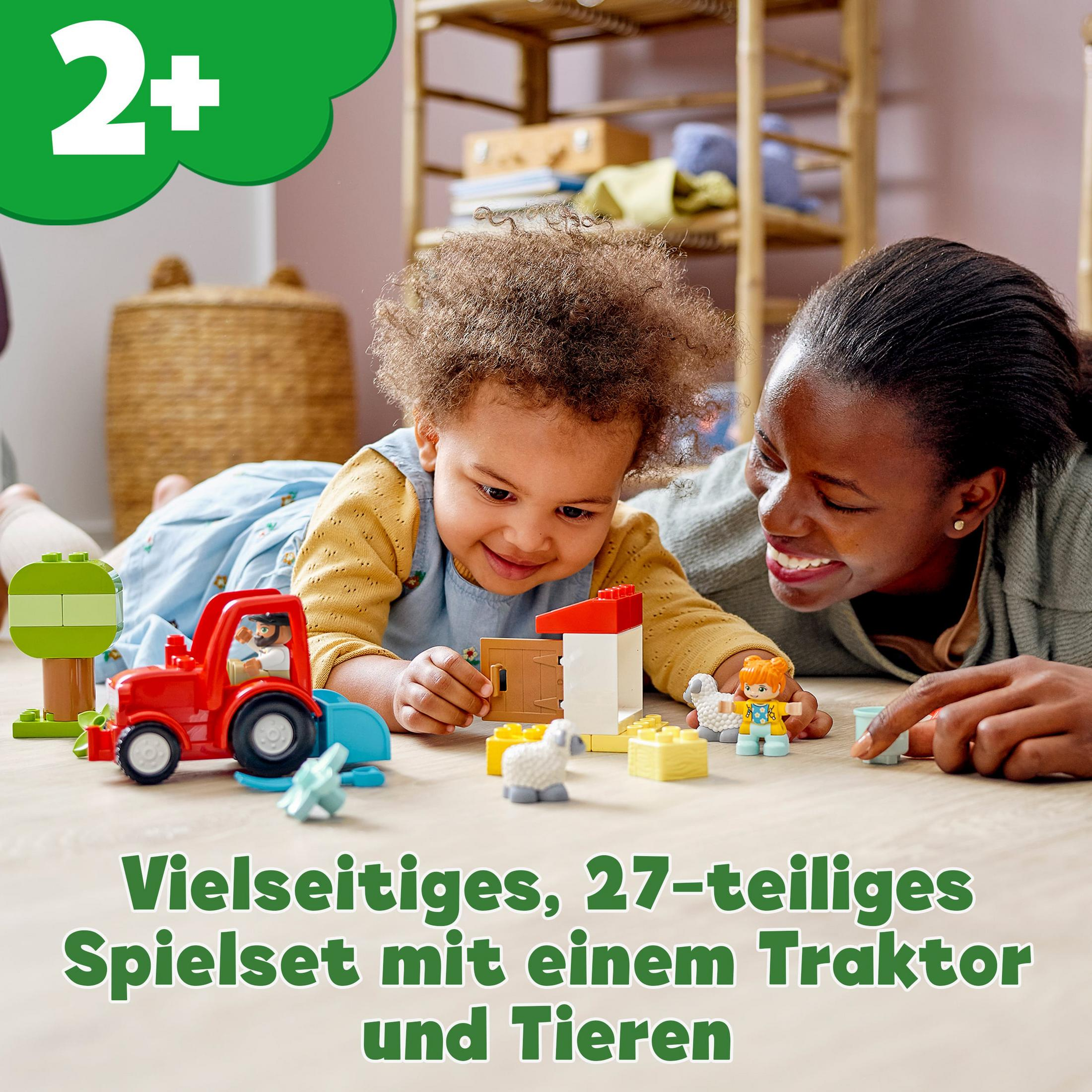 Mutter und Kind spielen mit einem roten Traktorspielzeug mit Bauernhoftierfiguren.