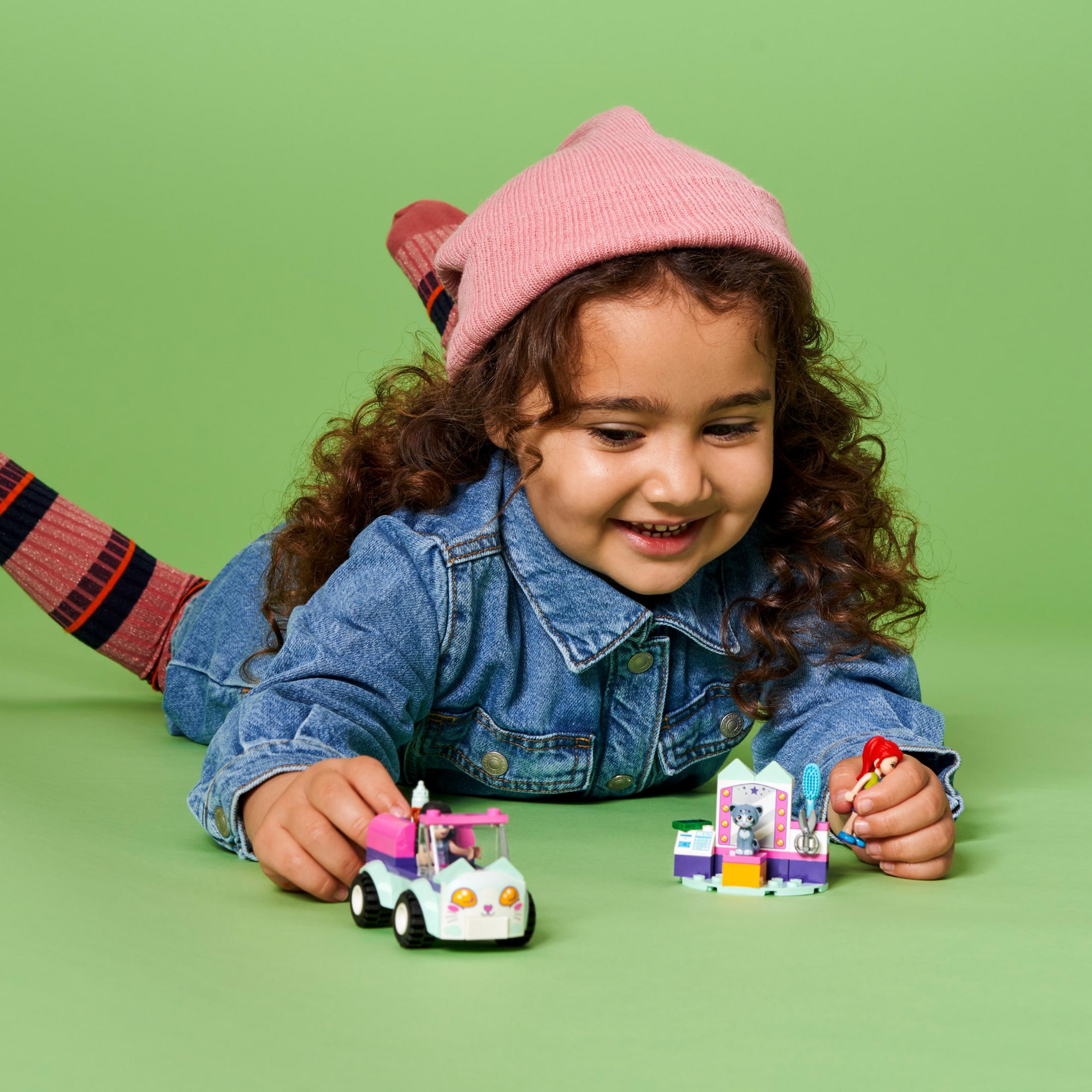 Ein Kind spielt mit LEGO Friends Spielzeug. Es gibt ein Spielzeugauto und einen Tierladen.