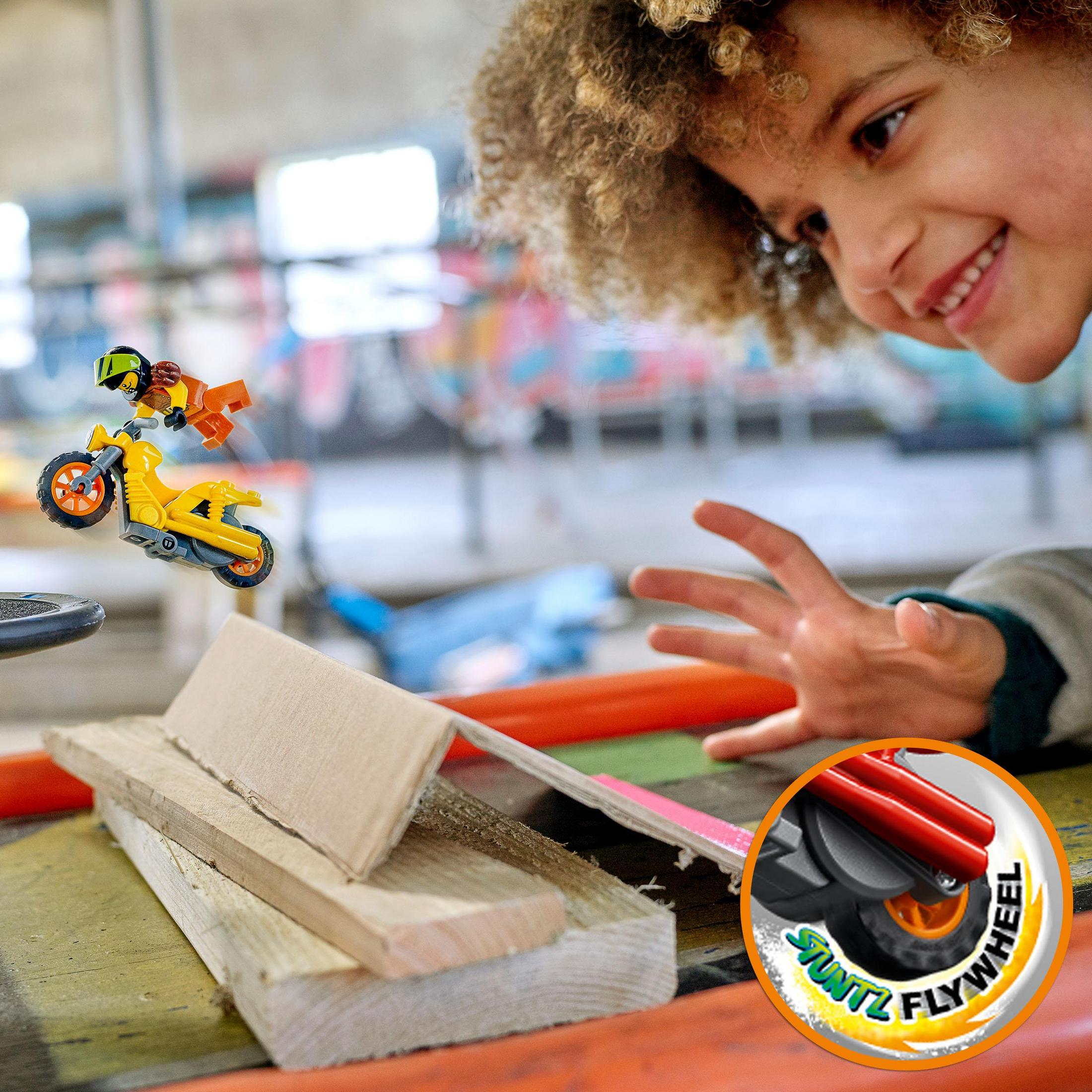Kind lächelt, beobachtet Motorradspielzeug in Aktion. Lego Stuntz Set, mit Rampen und Hindernissen.