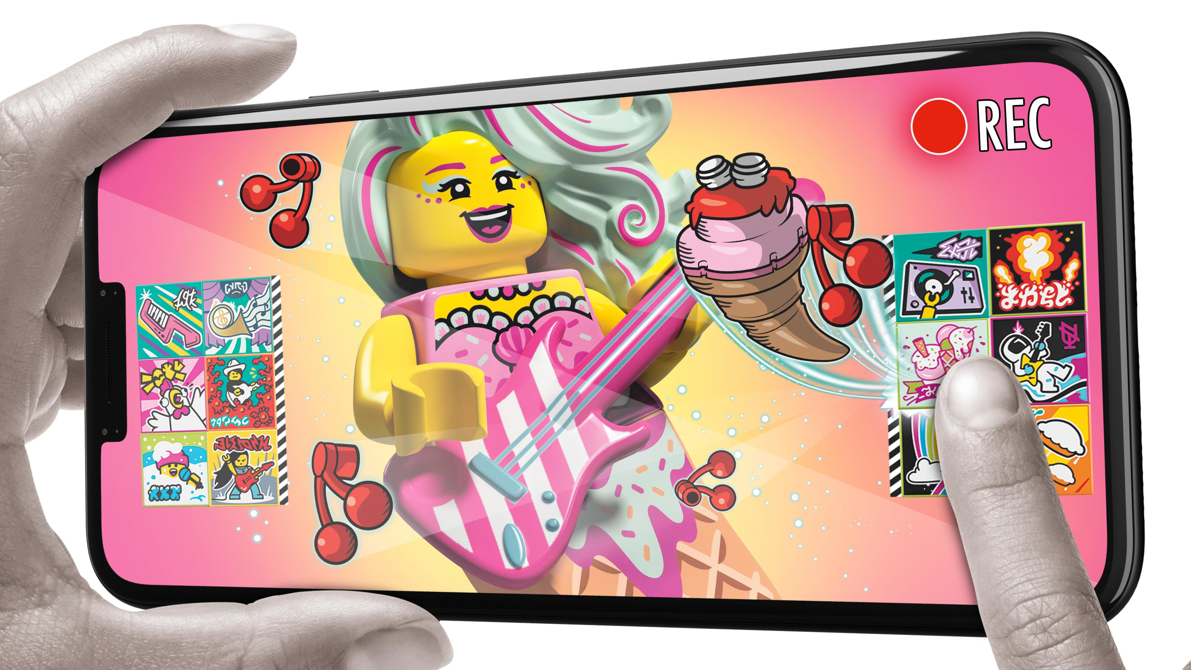 Ręka trzyma telefon z kreskówkowym wizerunkiem figurki Lego na ekranie.