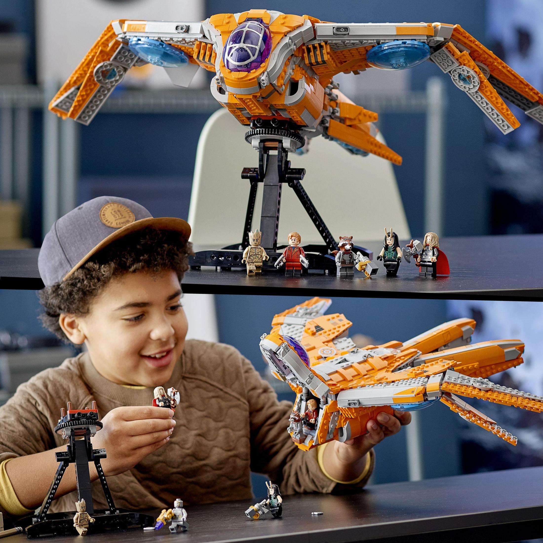 Ein Kind spielt mit einem Lego-Set eines Raumschiffs und Figuren. Das Set ist orange und blau mit Charakteren.