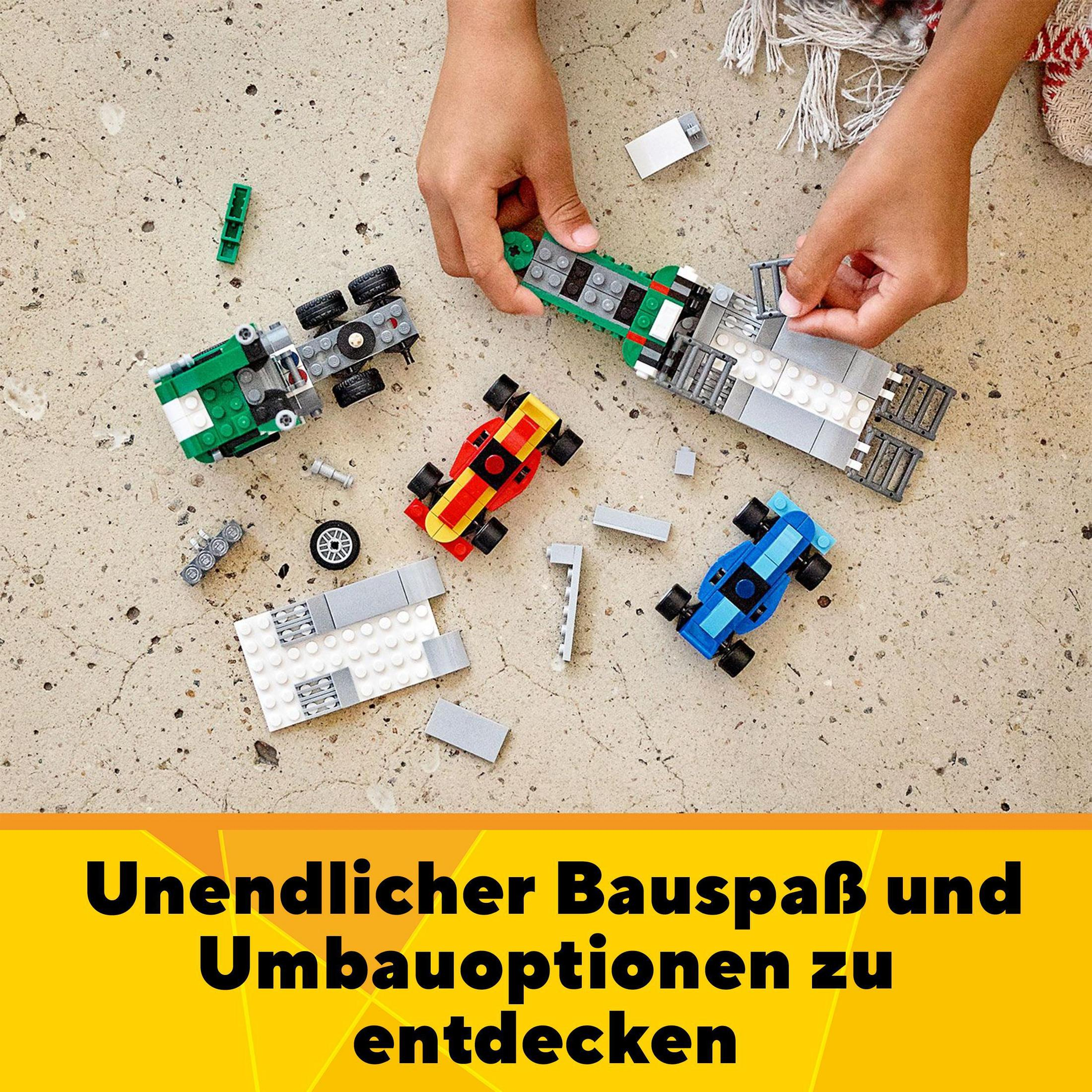 Hände montieren Spielzeugautos auf einer Oberfläche, mit verschiedenen farbigen Blöcken und Autoteilen sichtbar.