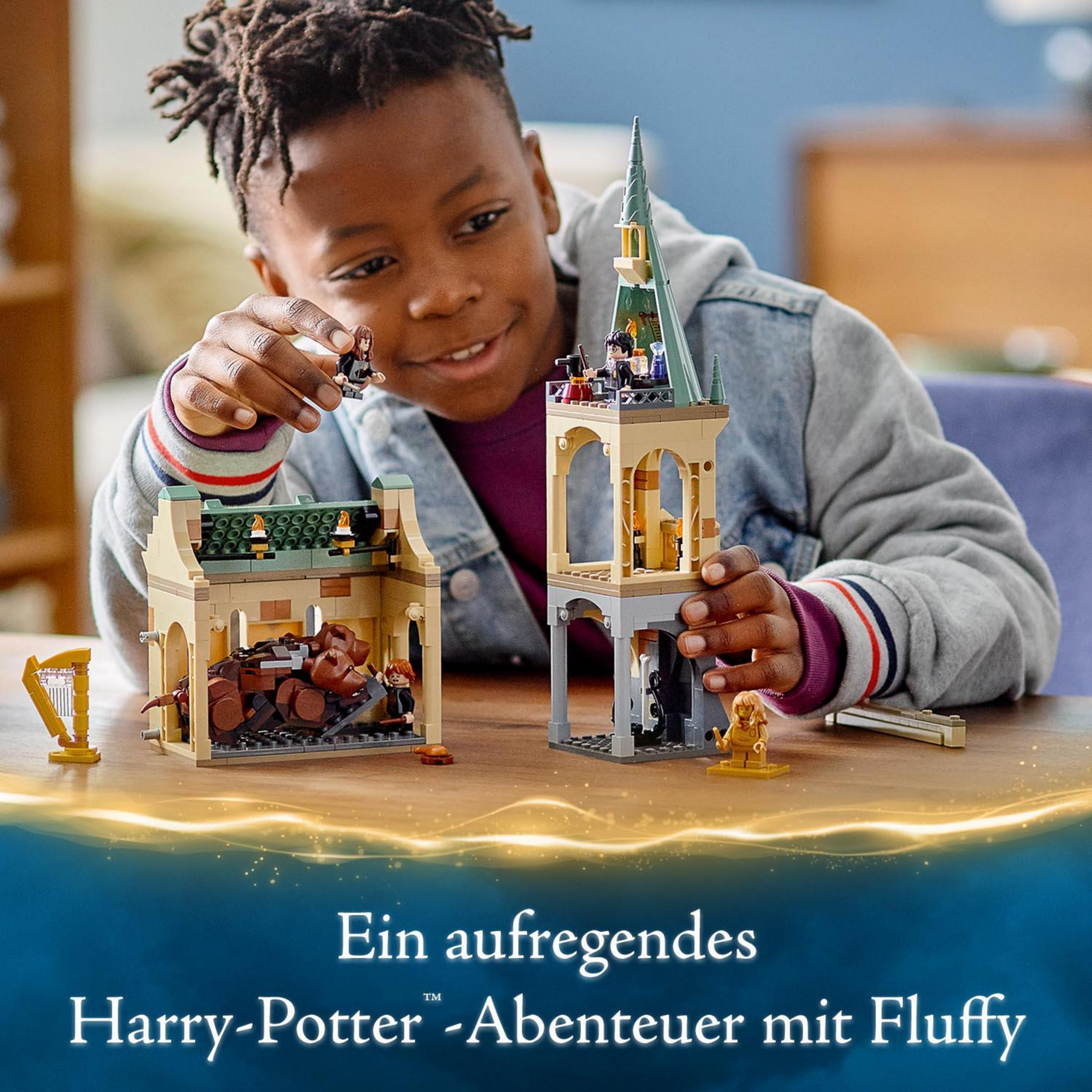 Un ragazzino gioca con un set Lego di Harry Potter. Due edifici sono sul tavolo.